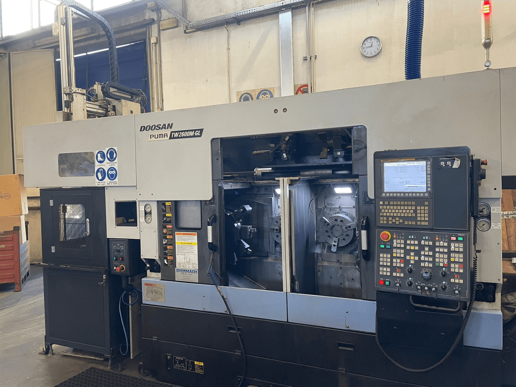 Токарный станок с ЧПУ Doosan Puma TW2600M GL, вид спереди, демонстрирует цифровую панель управления и внутреннюю часть станка с держателями инструментов.