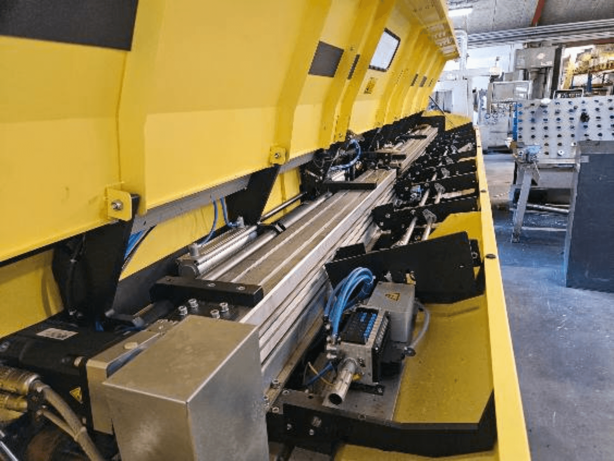 Крупный план желтой гидравлической машины с металлическими элементами и конвейерными дорожками, со шлангами и электронными деталями.