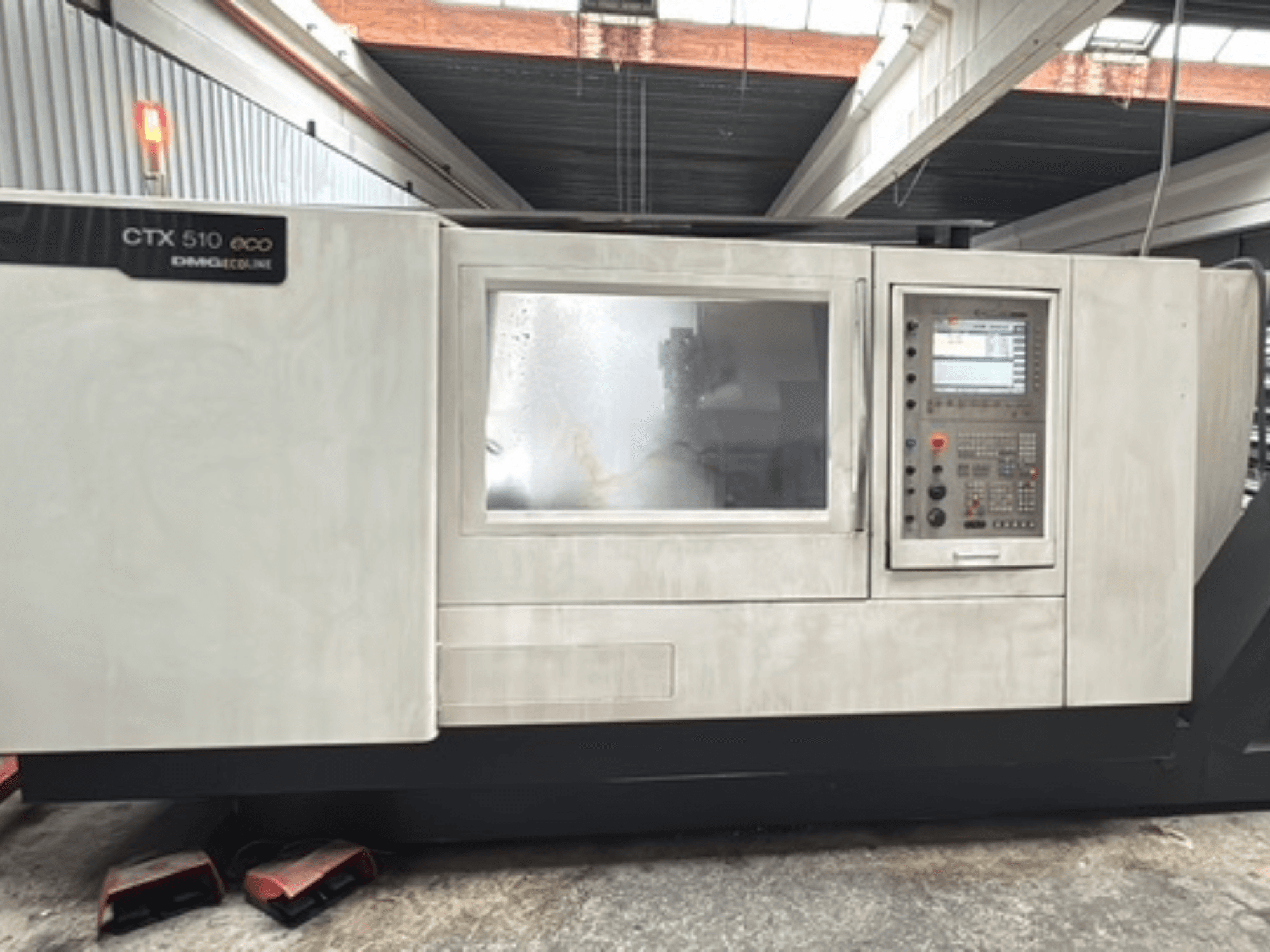 Горизонтальный токарный станок DMG CTX 510 ecoline, вид спереди, на котором видны панель управления и окно на корпусе станка.