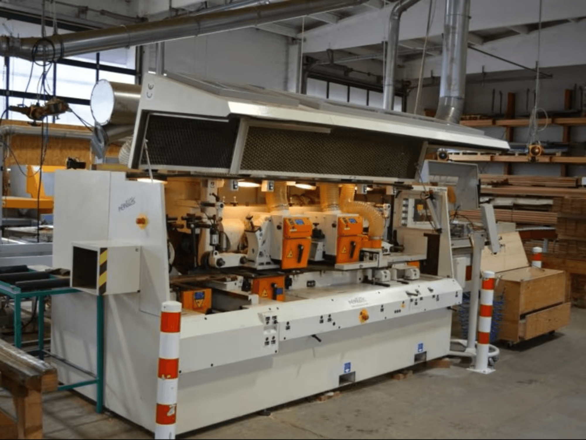 Деревообрабатывающий станок PENIGAS, вид спереди, с двумя оранжевыми режущими головками и системой удаления пыли в мастерской.