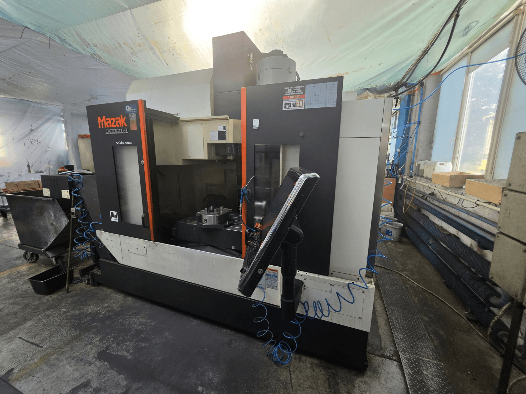Вертикальный обрабатывающий центр Mazak VCN-530C в виде спереди, на котором видны панель управления, рабочая зона и держатель инструмента.