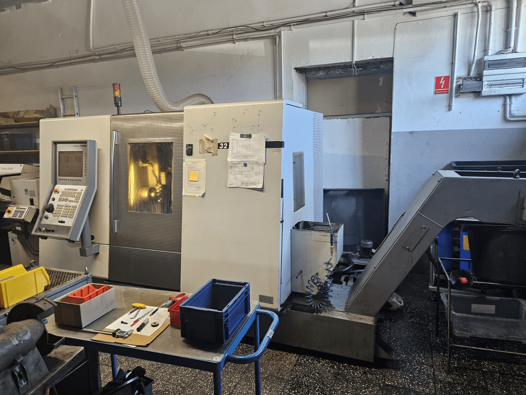 Многошпиндельный токарный станок DMG GILDEMEISTER Sprint 32 linear, вид спереди в мастерской, видны панель управления и инструменты.