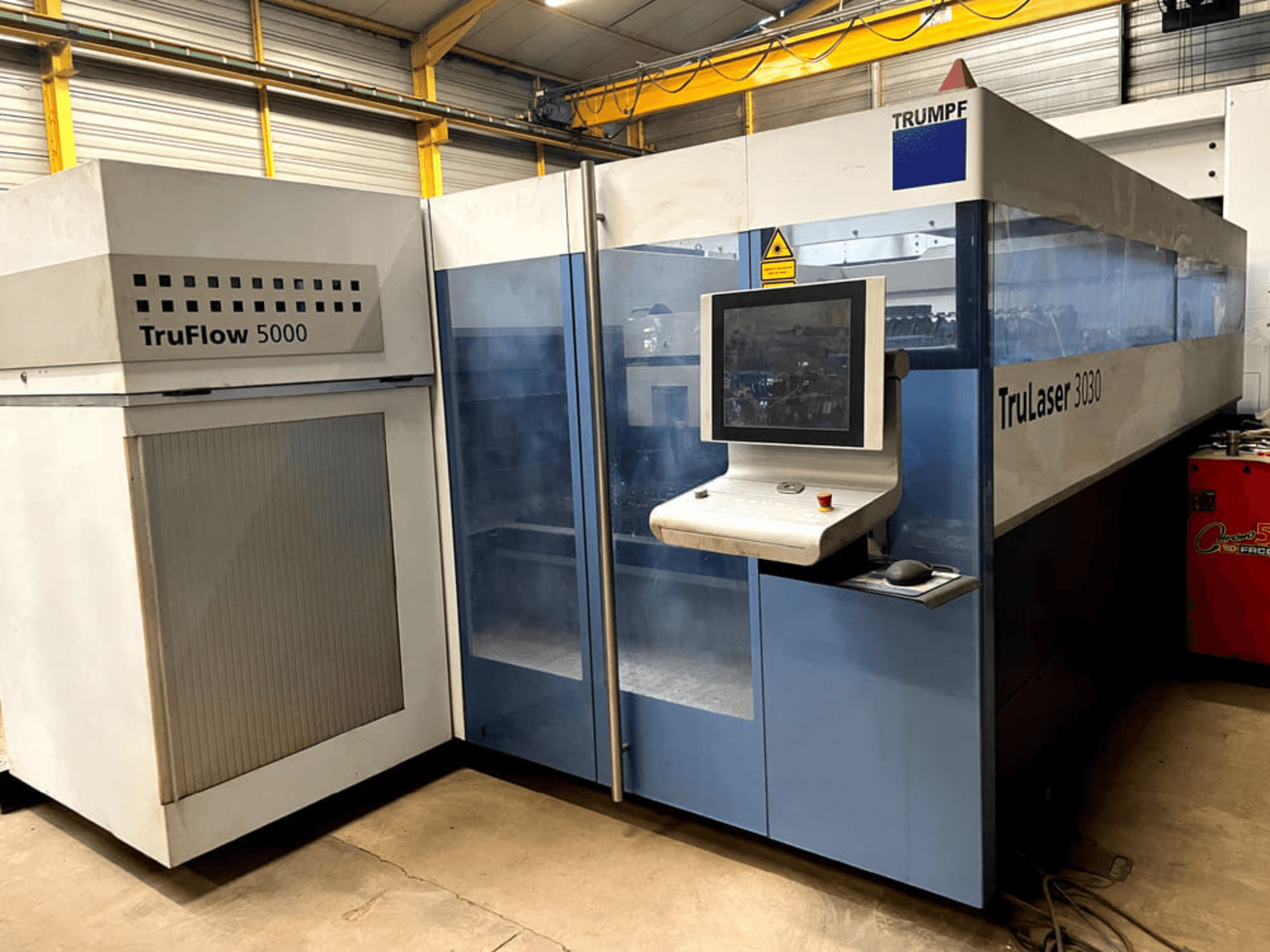 Лазерный резак TRUMPF TruLaser 3030 с CO₂-лазером, вид спереди, с панелью управления и расположенным рядом блоком TruFlow 5000.