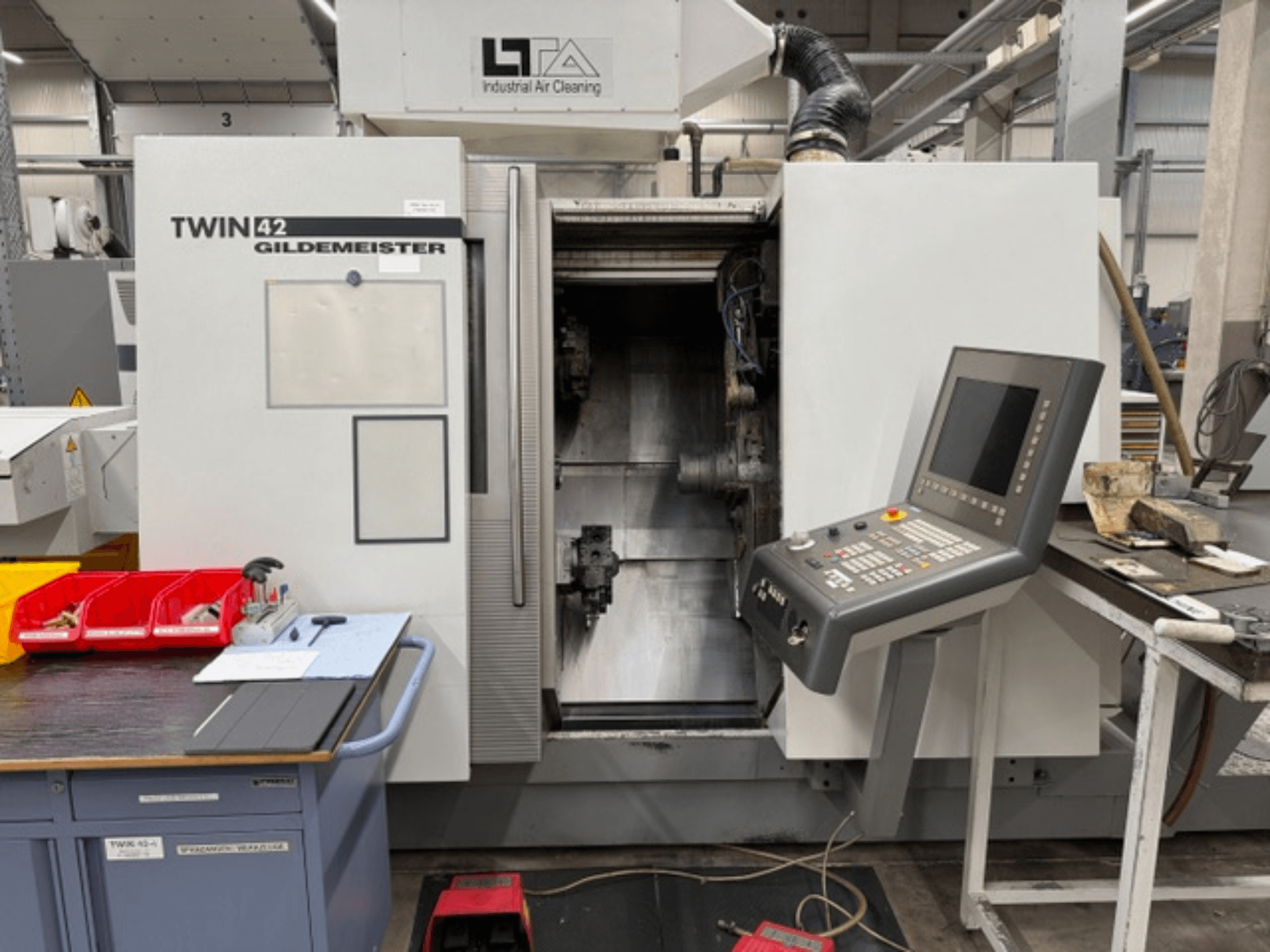 Горизонтальный токарный станок Gildemeister TWIN 42, вид спереди с панелью управления и открытой рабочей зоной.