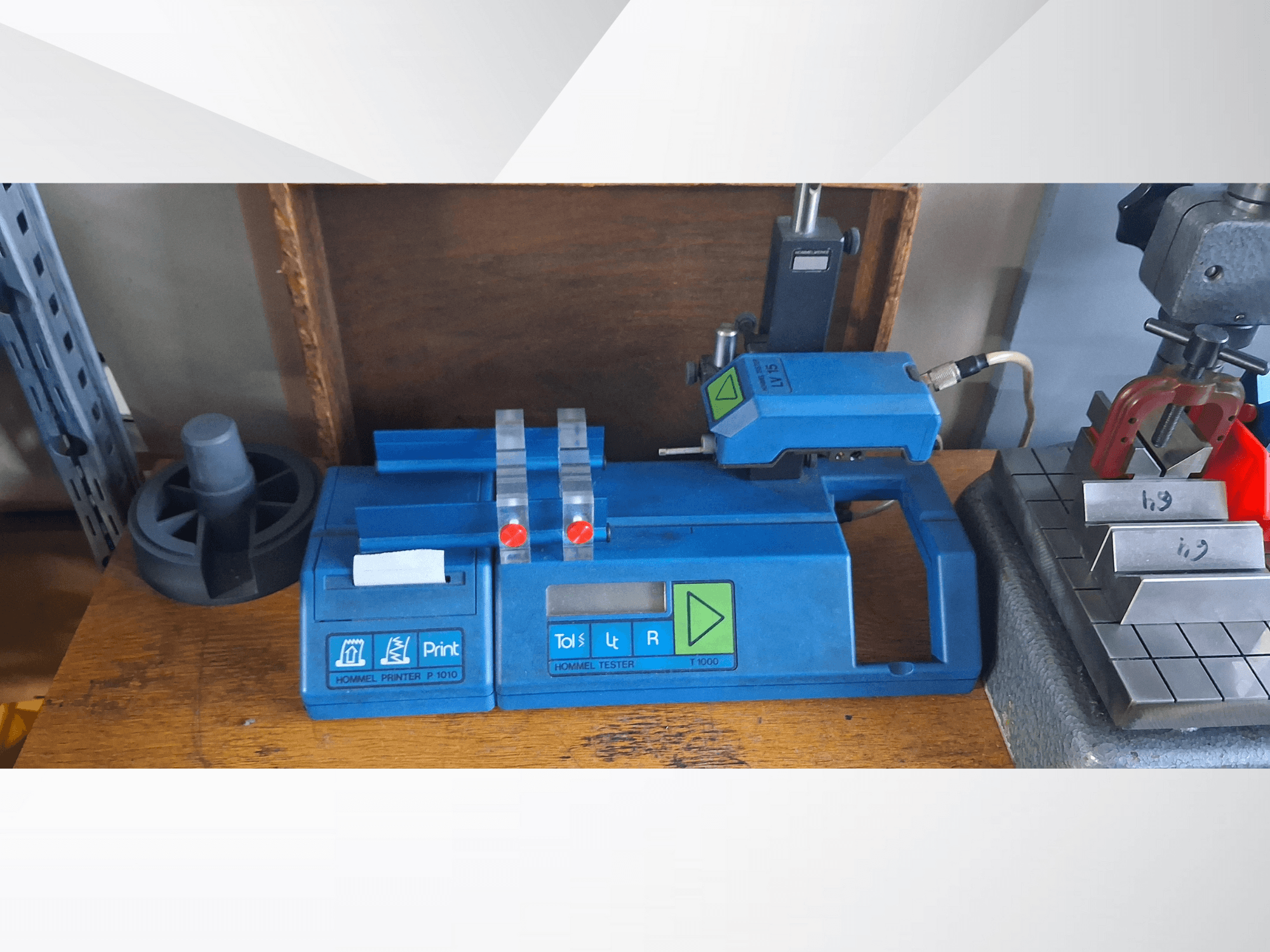 Принтер Hommel P 1010 и тестер T1000 в синем корпусе, с кнопками и красными индикаторами, на верстаке, вид сбоку.