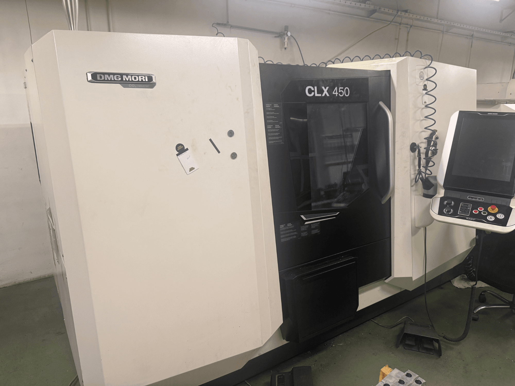Станок с ЧПУ DMG MORI CLX 450, вид сбоку с панелью управления, видимые кнопки управления и чистое рабочее пространство.