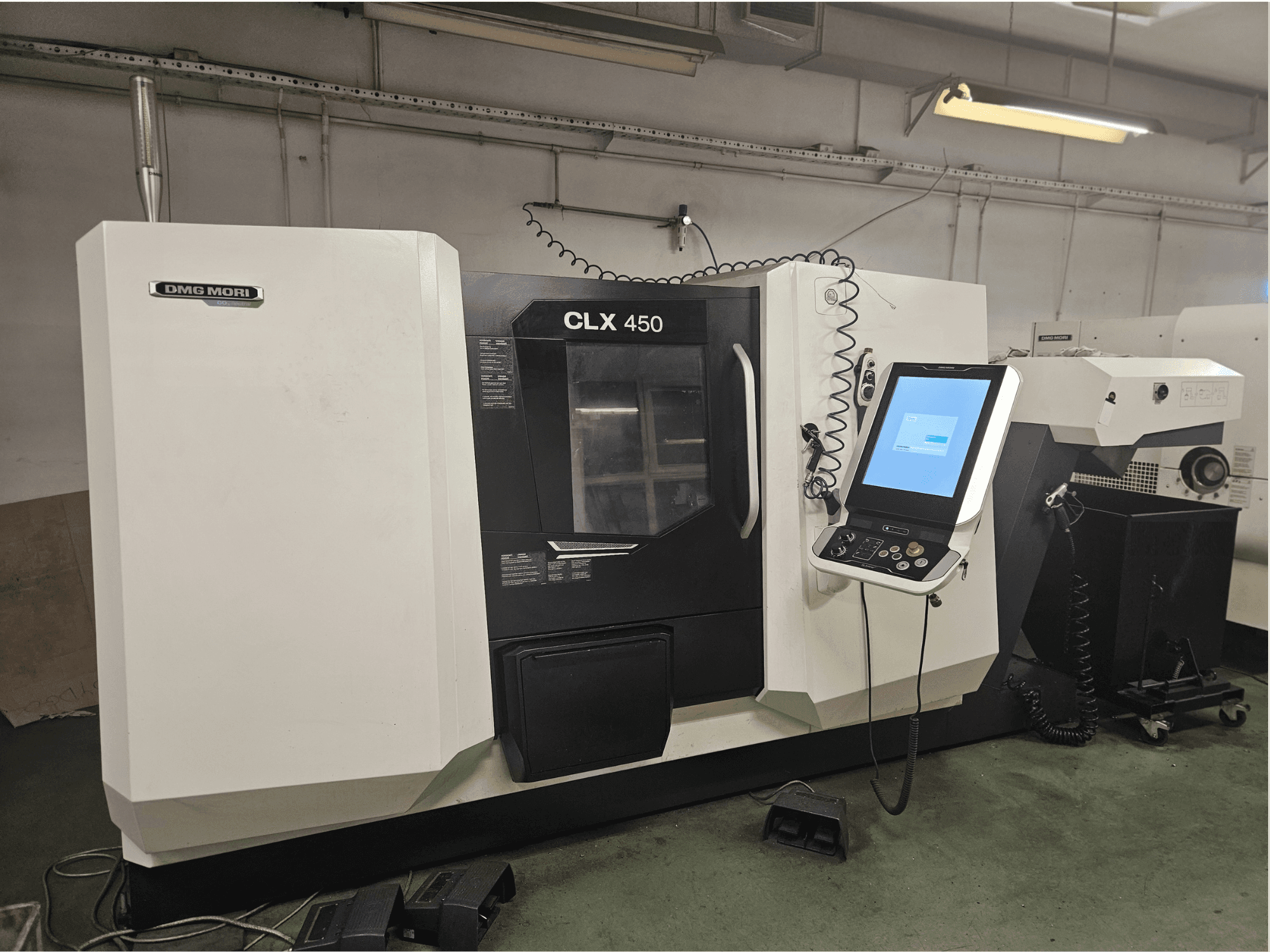 Станок с ЧПУ DMG MORI CLX 450 с видом спереди, с панелью управления и сенсорным дисплеем, установленный в мастерской.