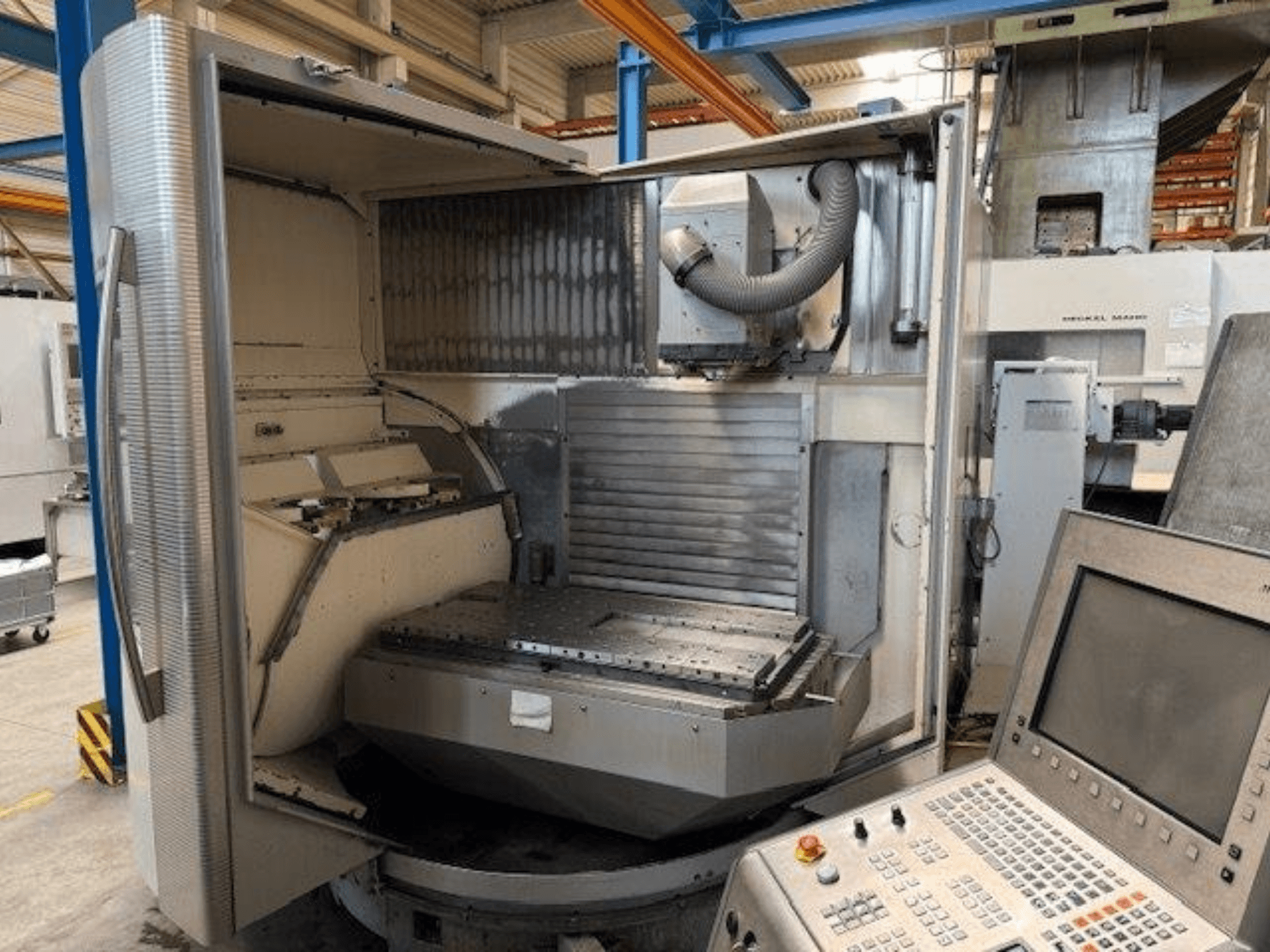 Вертикальный обрабатывающий центр DMG MORI DMU 80T, вид спереди с открытым корпусом и панелью управления.