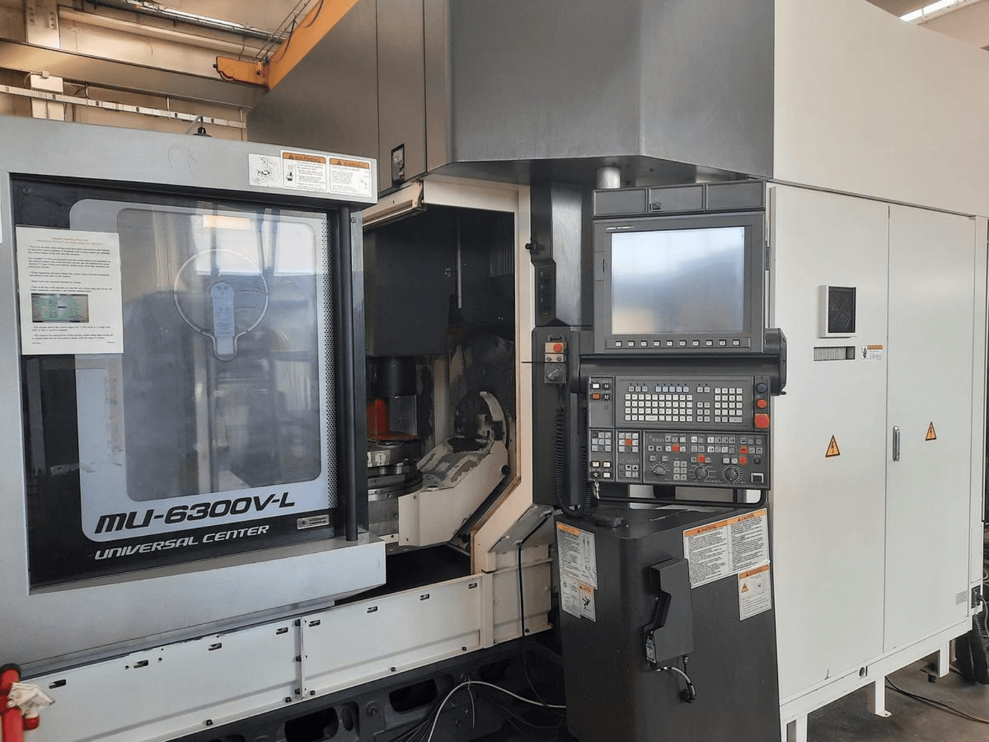 Станок MU-6300V-L Universal Center показан спереди, видны панель управления, экран и инструкции по эксплуатации.
