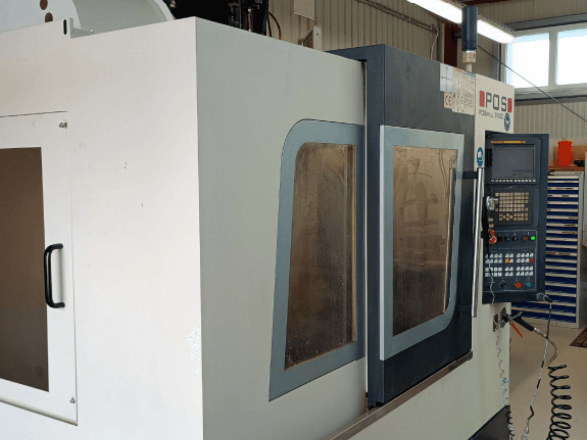 Вертикальный обрабатывающий центр POSmill B 800, вид спереди, с панелями управления и окнами из безопасного стекла.