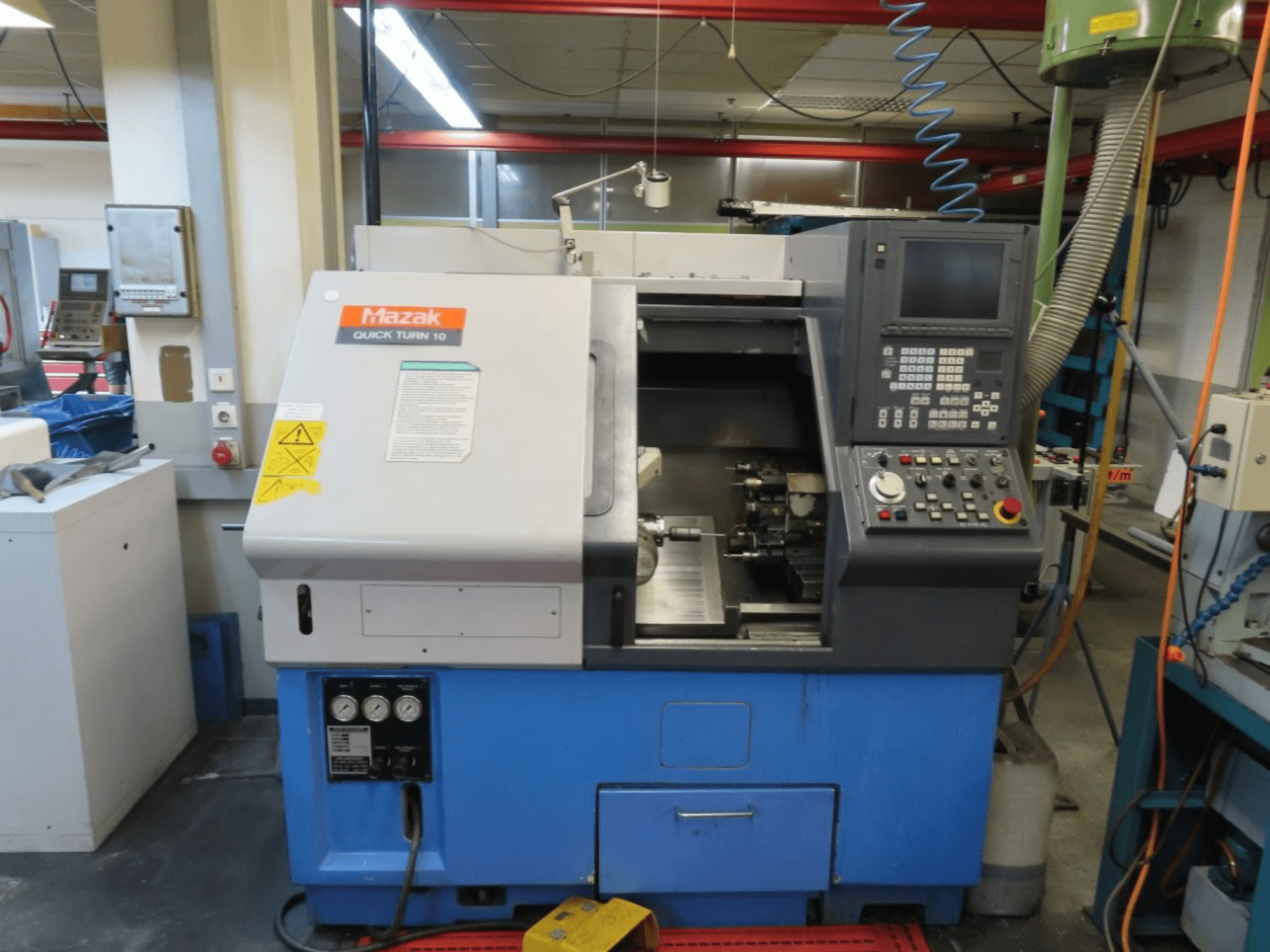 Горизонтальный токарный станок Mazak Quick Turn 10 в виде спереди с панелью управления, шпинделем и системой подачи охлаждающей жидкости.