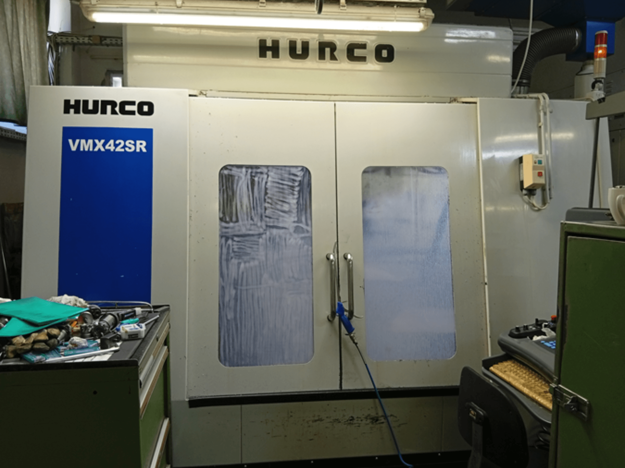 Вертикальный обрабатывающий центр Hurco VMX 42SR на переднем плане: синяя панель, интерфейс управления и чистое рабочее пространство.
