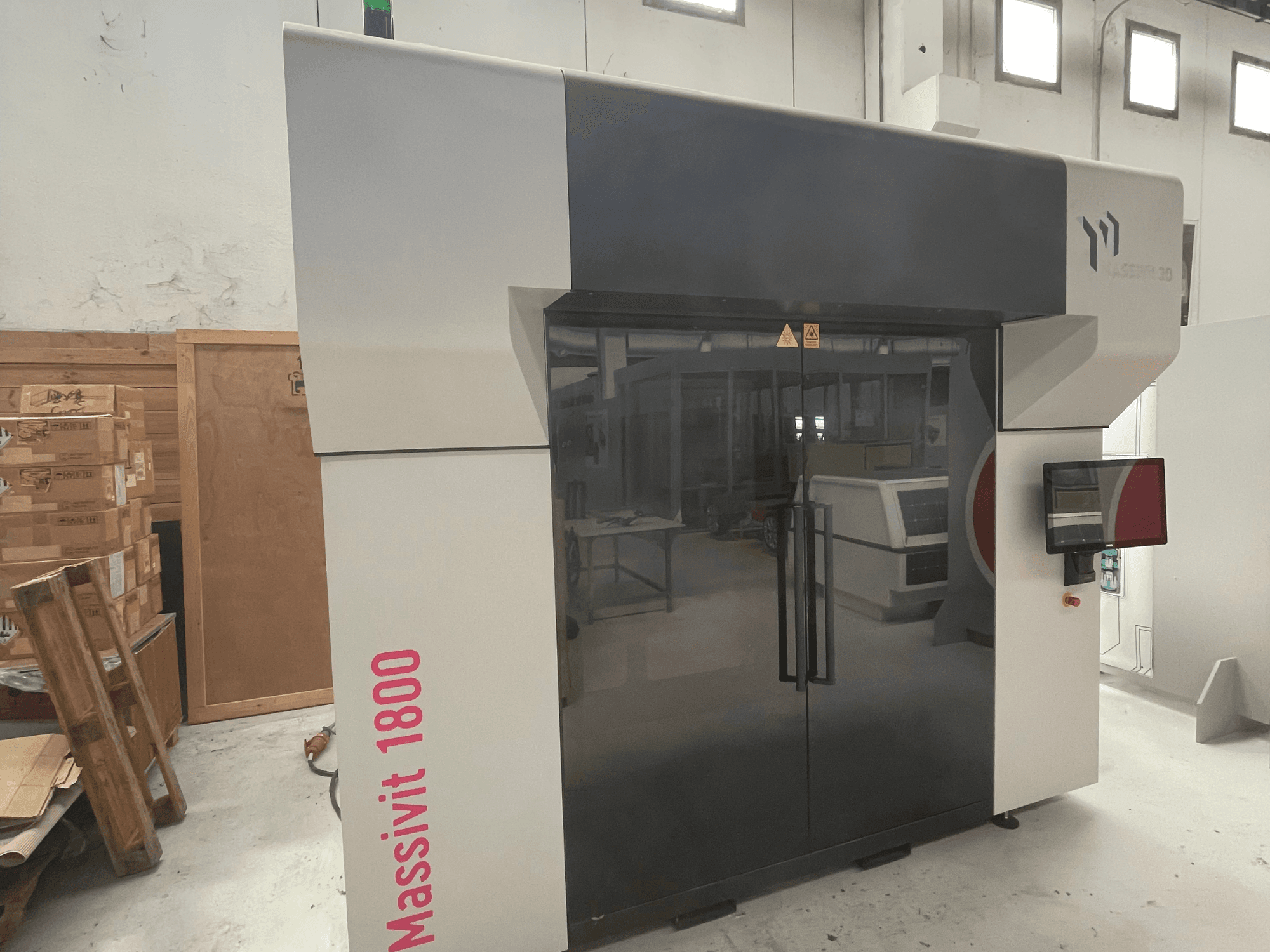 3D-принтер Massivit 1800 для печати из пластика, представленный в виде бокового вида, оснащен сенсорным экраном и отличается лаконичным черно-белым дизайном.