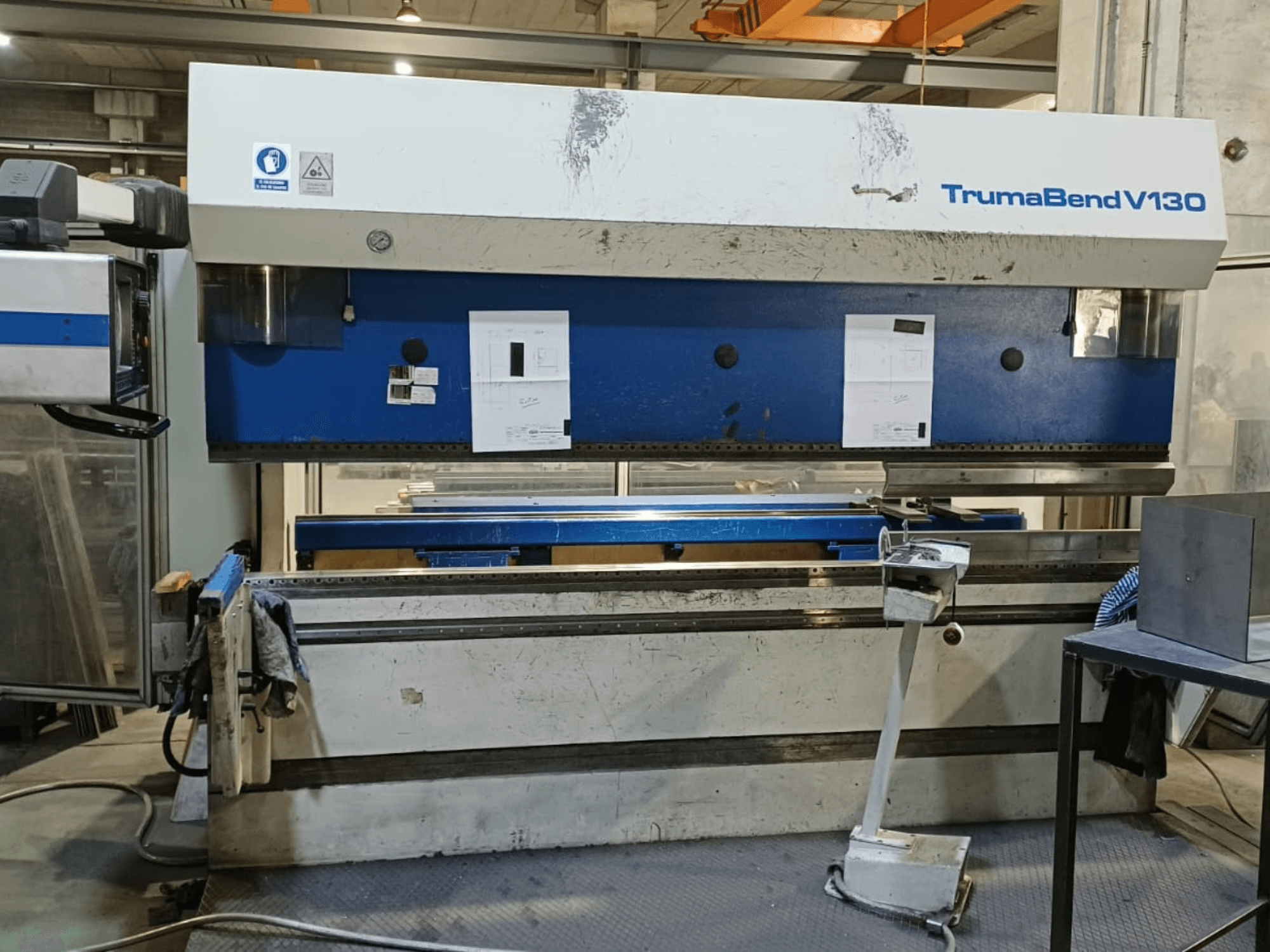 Гибочный пресс TRUMPF Trumatic Trumabend V130 в виде спереди, на котором видны панель управления, рабочая поверхность и регулируемые инструменты.