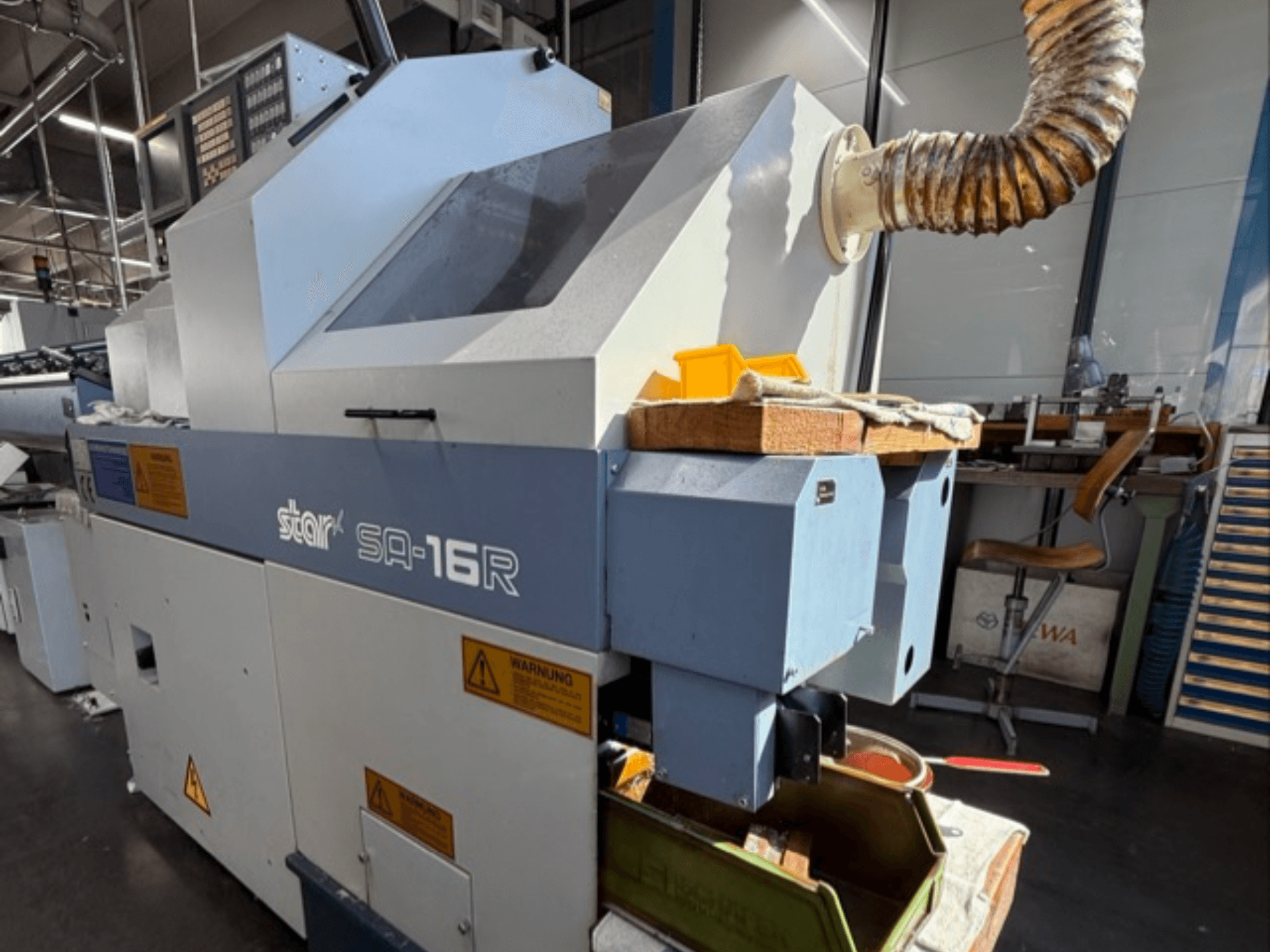 Станок Stark SA-16R спереди, с конической выхлопной трубой и рабочей зоной с желтыми инструментами и предупреждающими надписями.