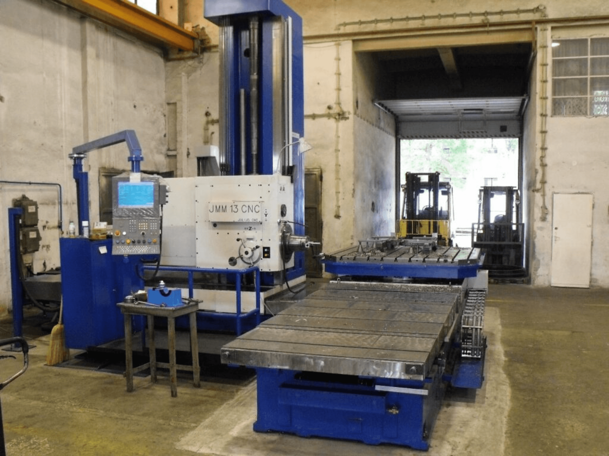 Фрезерный станок с ЧПУ JMM 13 в мастерской, вид спереди, панель управления, большой рабочий стол и промышленный фон.