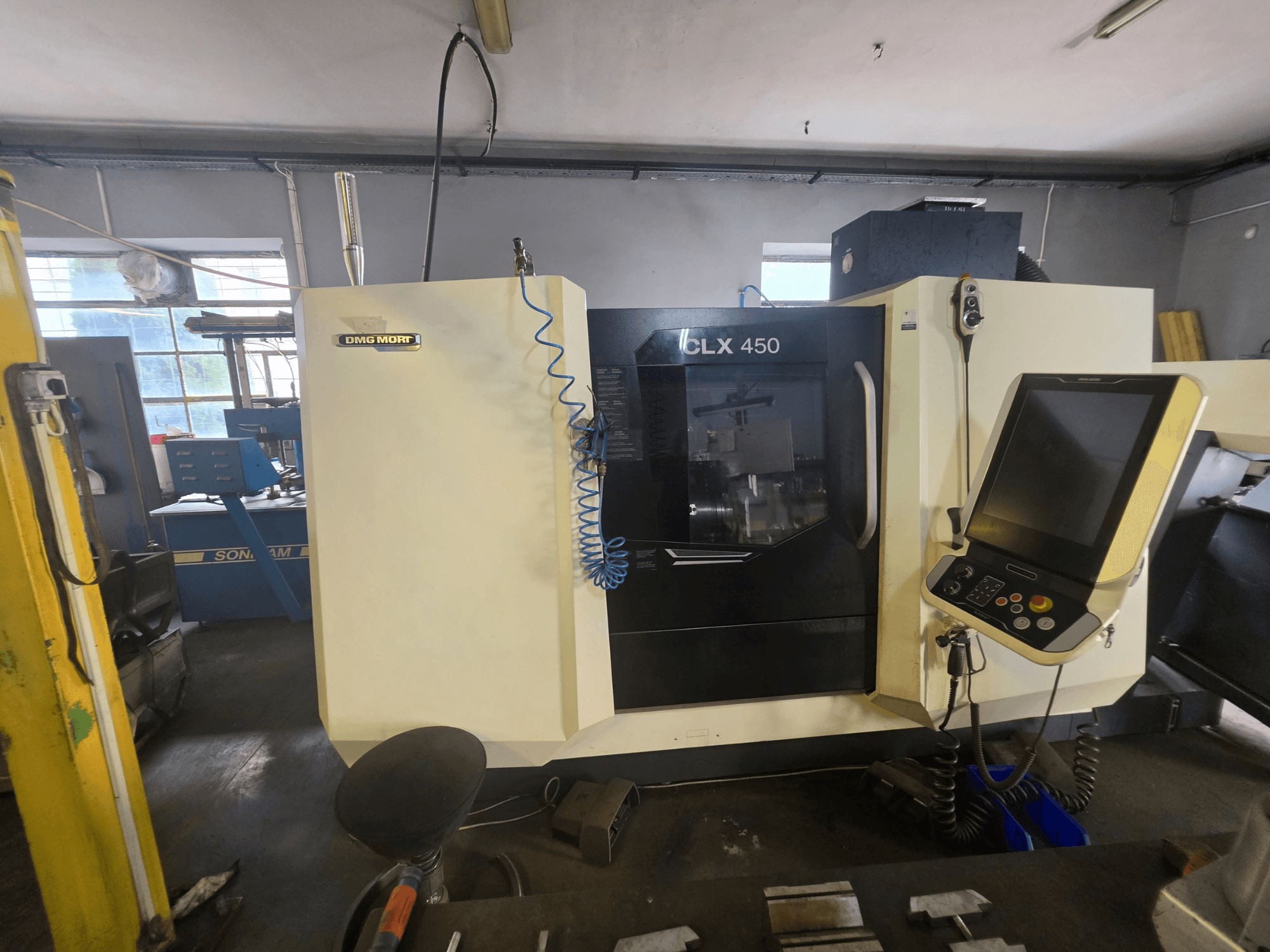 Горизонтальный токарный станок DMG MORI CLX 450 V6, вид спереди, с панелью управления и заметным логотипом.
