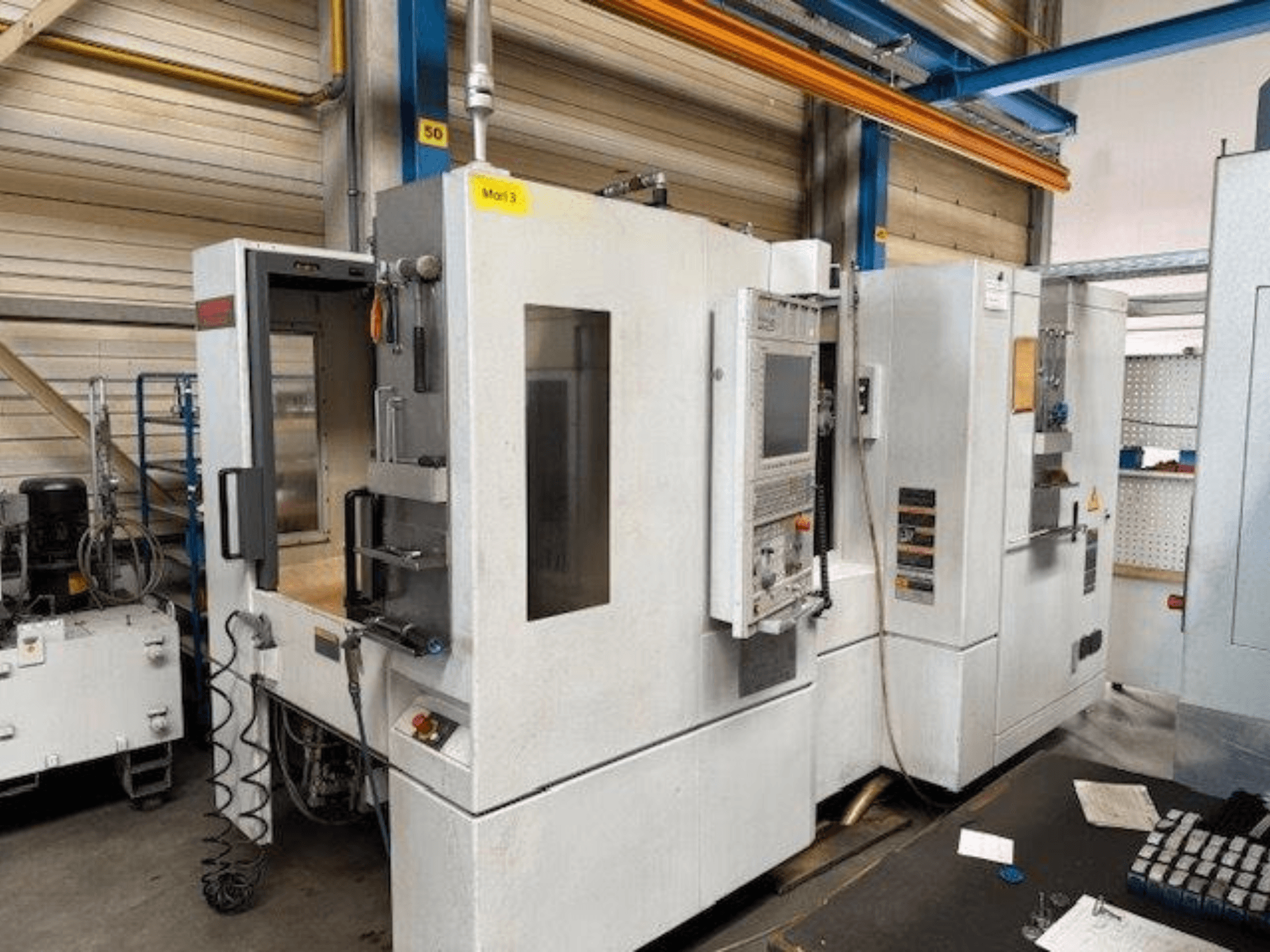 Вид спереди горизонтального обрабатывающего центра MORI SEIKI NH4000 DCG с открытой дверью и панелью управления, показывающей рабочее пространство.