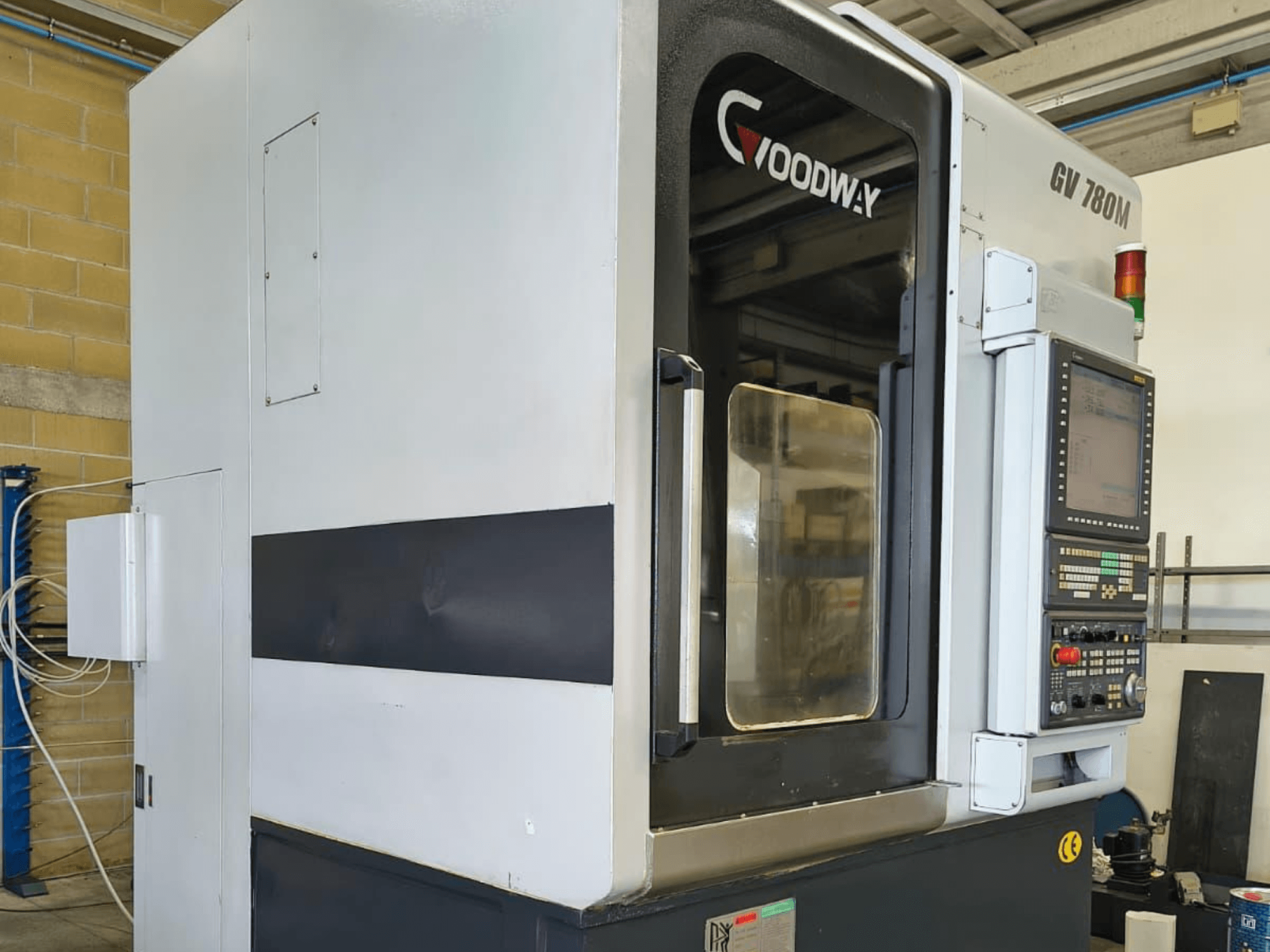 Вертикальный токарный станок Goodway GV 780 M, вид сбоку, демонстрирует панель управления, функции безопасности и чистый внешний дизайн.