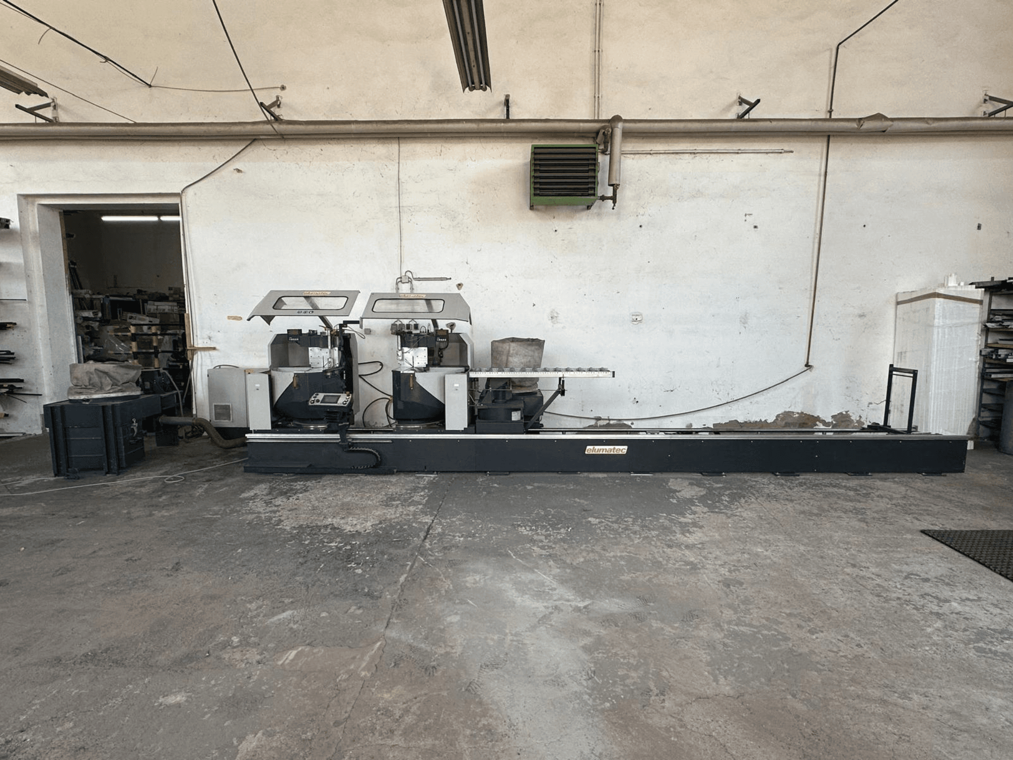 Циркулярная пила по металлу Elumatec DG 244 в мастерской, вид сбоку с двумя пилами и органами управления на прочном основании.