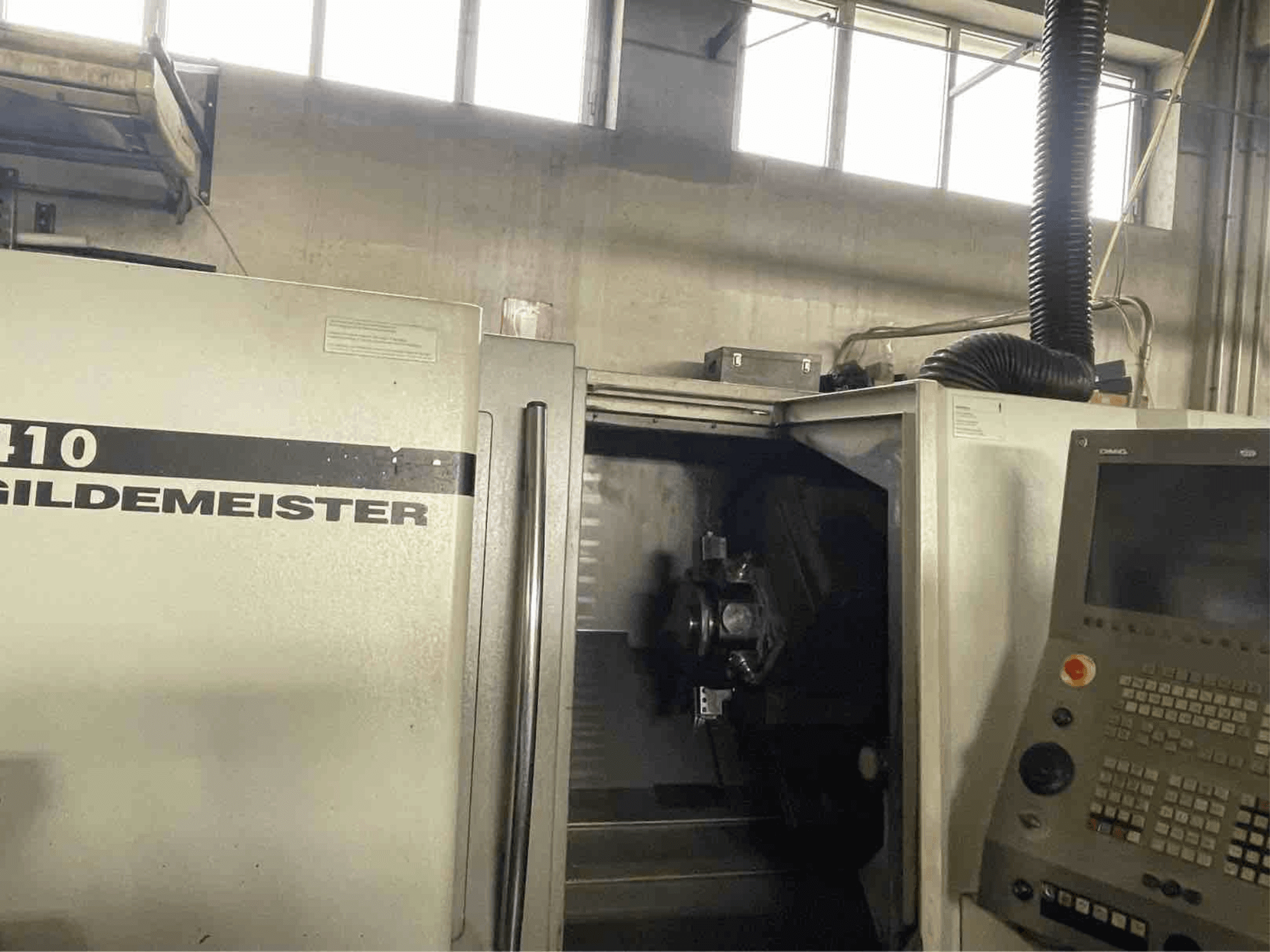 Горизонтальный токарный станок DMG CTX410, вид спереди, панель управления и видимые обрабатывающие компоненты внутри.