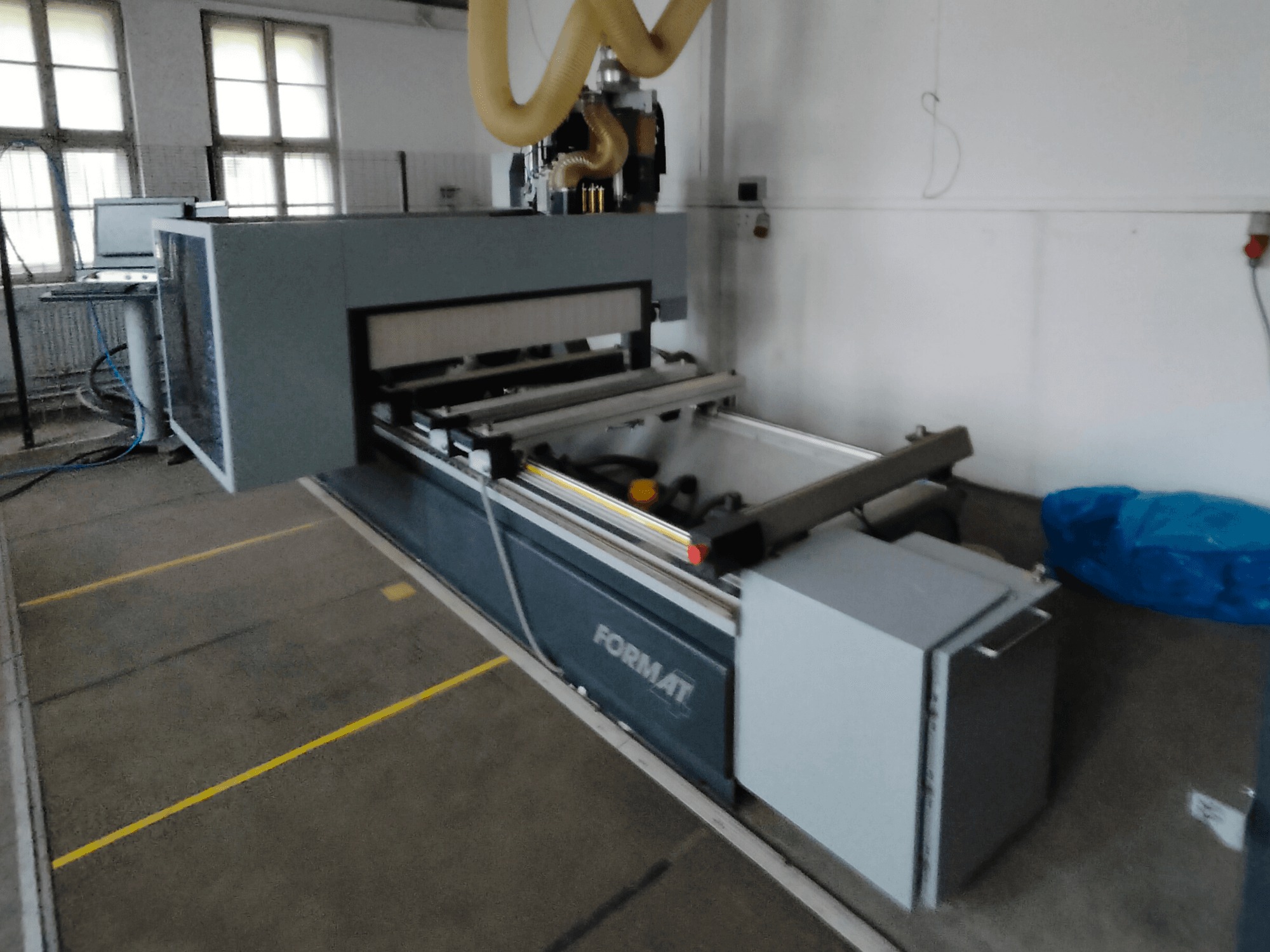 Вид спереди на форматный станок с ЧПУ с серым корпусом, направляющими и видимой панелью управления.