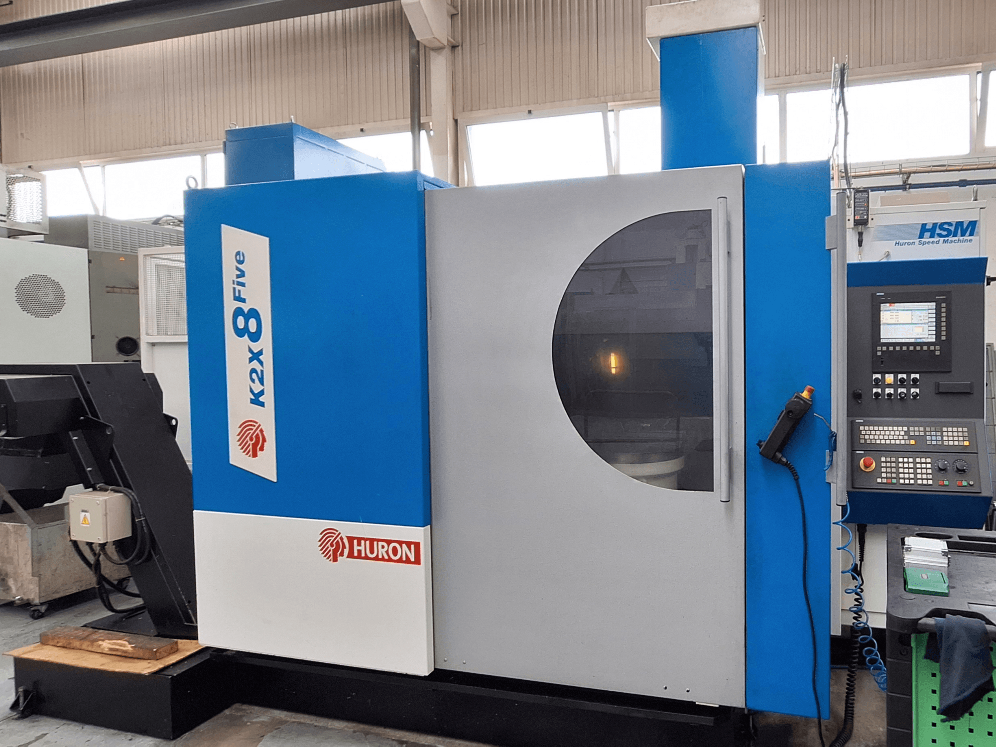 Портальный фрезерный станок Huron K2X 8 Five, вид спереди с панелью управления и большим смотровым окном.