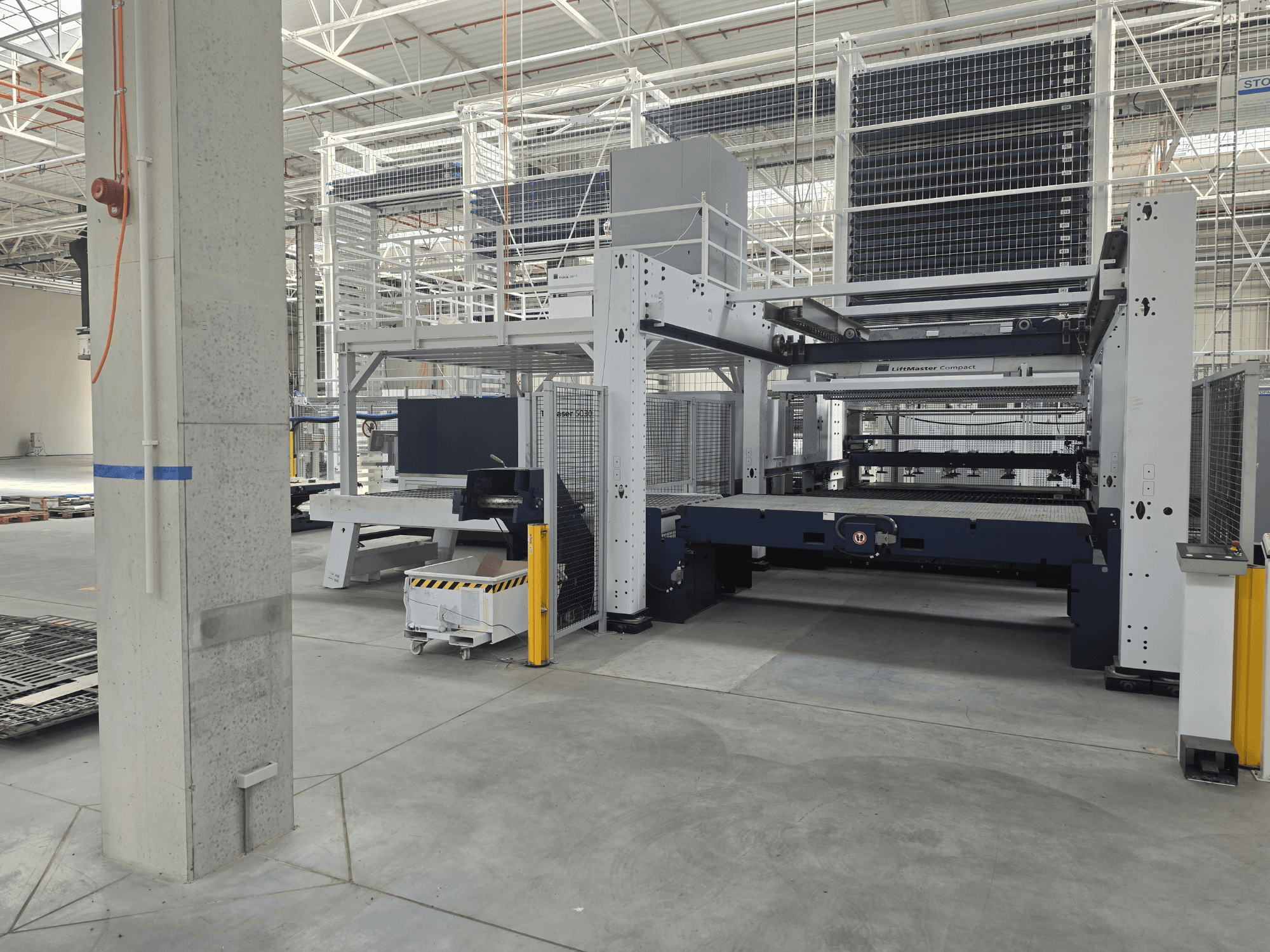 TRUMPF TruLaser 5030 fiber L76 FMC — вид спереди, демонстрирующий станок для лазерной резки с волоконным лазером в просторном промышленном помещении.