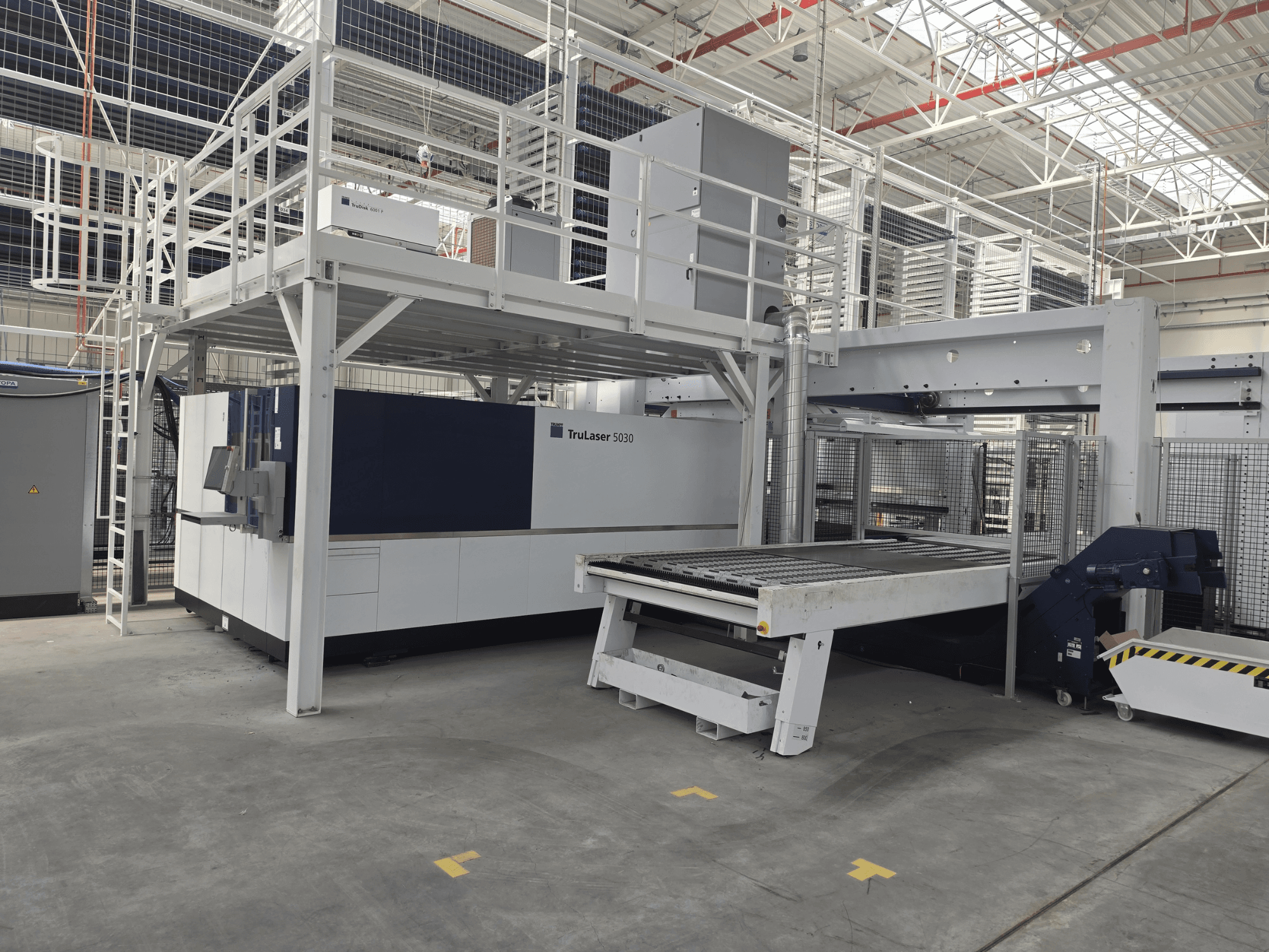 Станок TRUMPF TruLaser 5030 fiber L76 FMC в цехе, вид спереди, на котором видны зона резки и механизм загрузки/разгрузки.