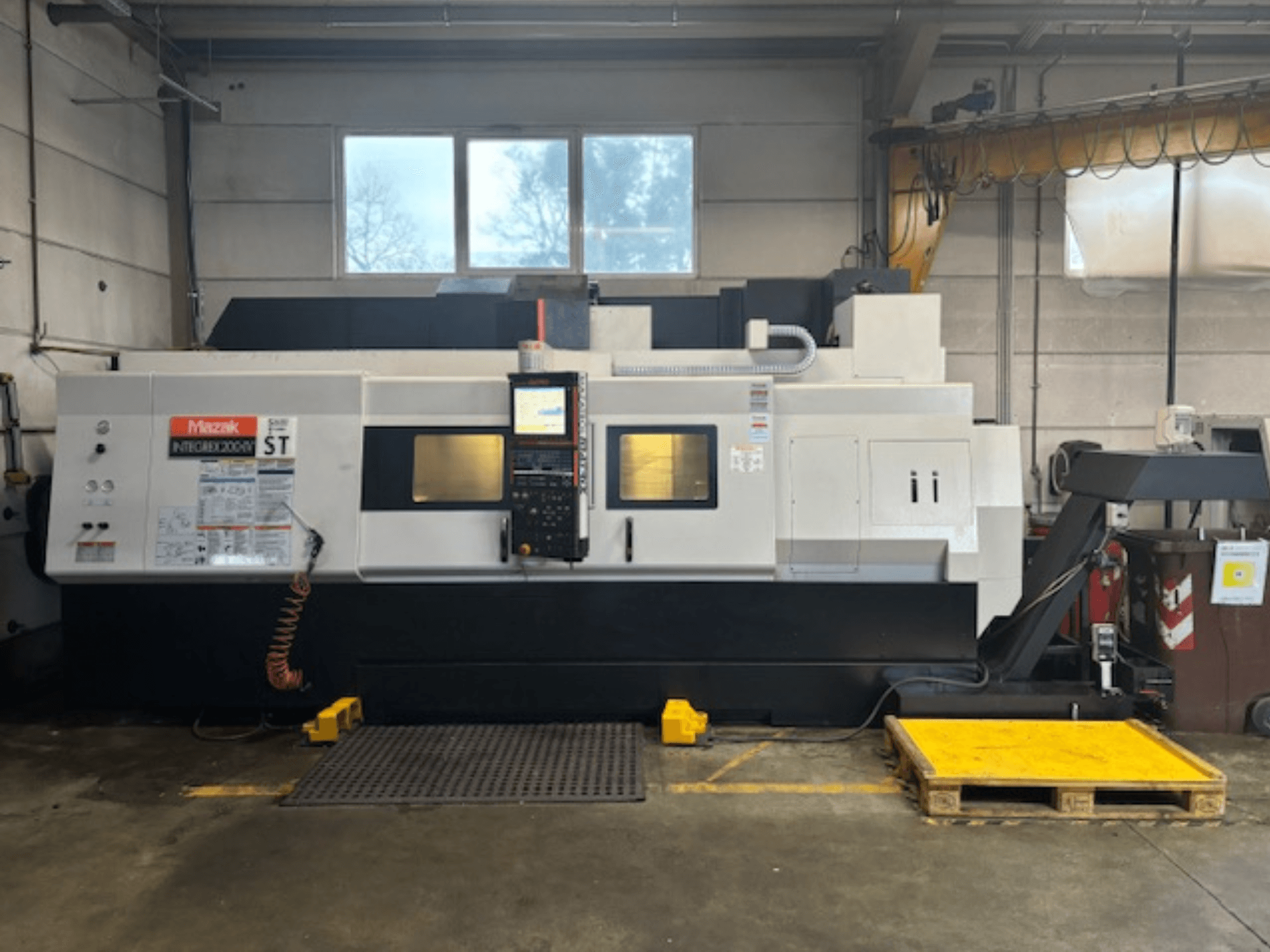 Mazak Integrex 200 SY ST, вид сбоку, панель управления, индикаторы работы и линии подачи охлаждающей жидкости в мастерской.