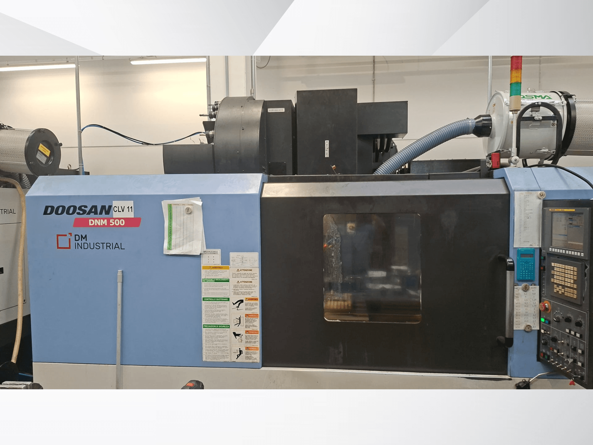 Вертикальный обрабатывающий центр DOOSAN DNM 500 в боковом виде с панелью управления и рабочими узлами.