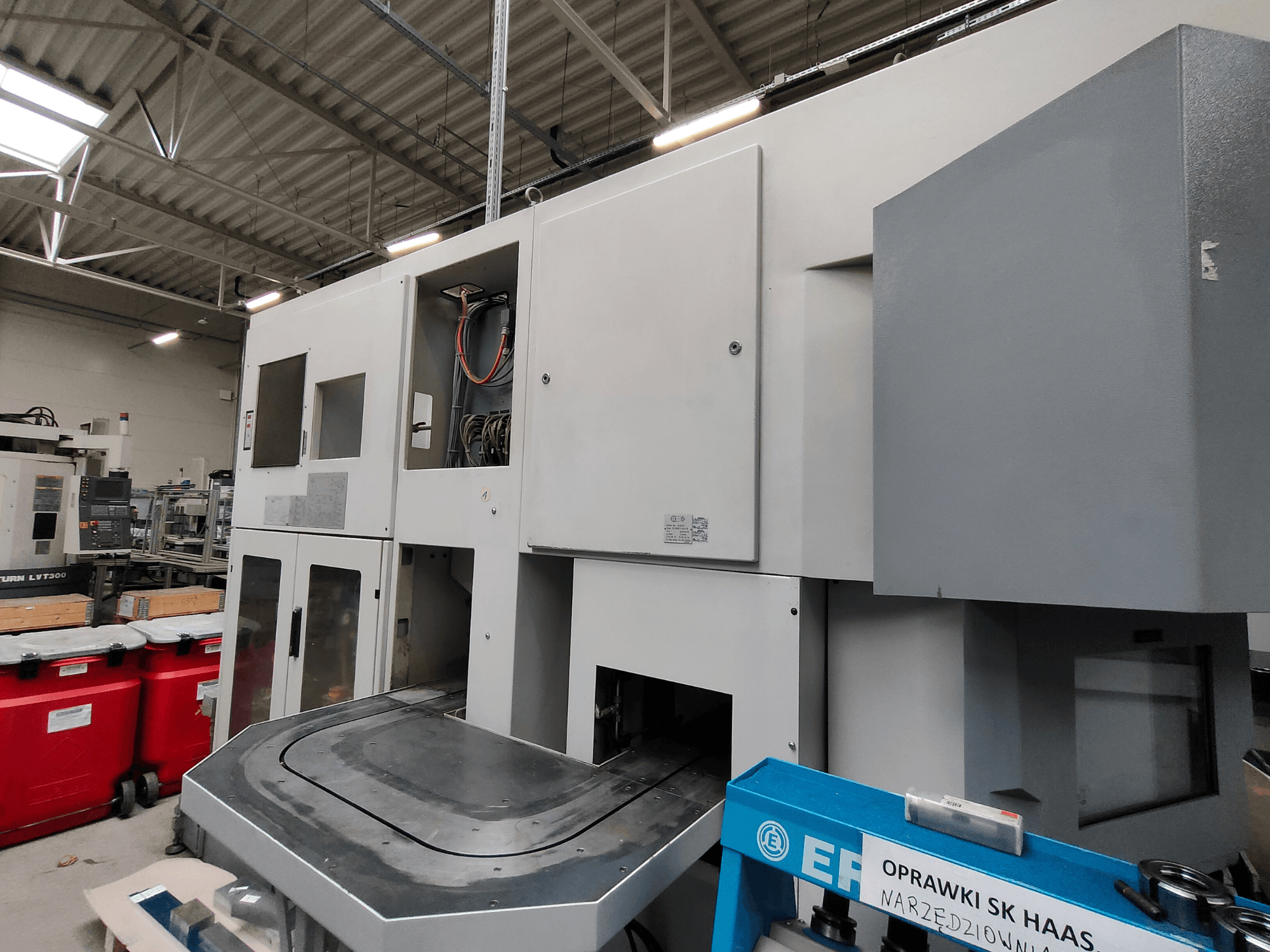 Вертикальный токарный станок EMAG VSC 250, показанный сбоку, с панелями управления и большой рабочей зоной.