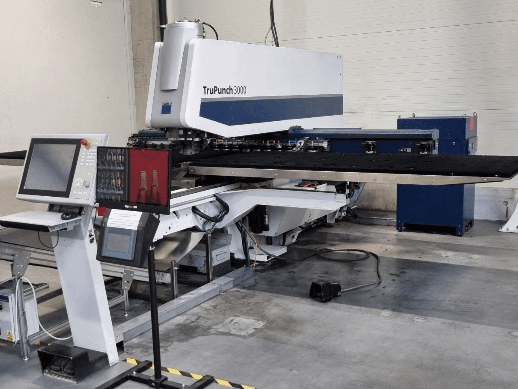 Штамповочный станок с ЧПУ TRUMPF TruPunch 3000, вид спереди, с панелью управления и большим штамповочным столом.