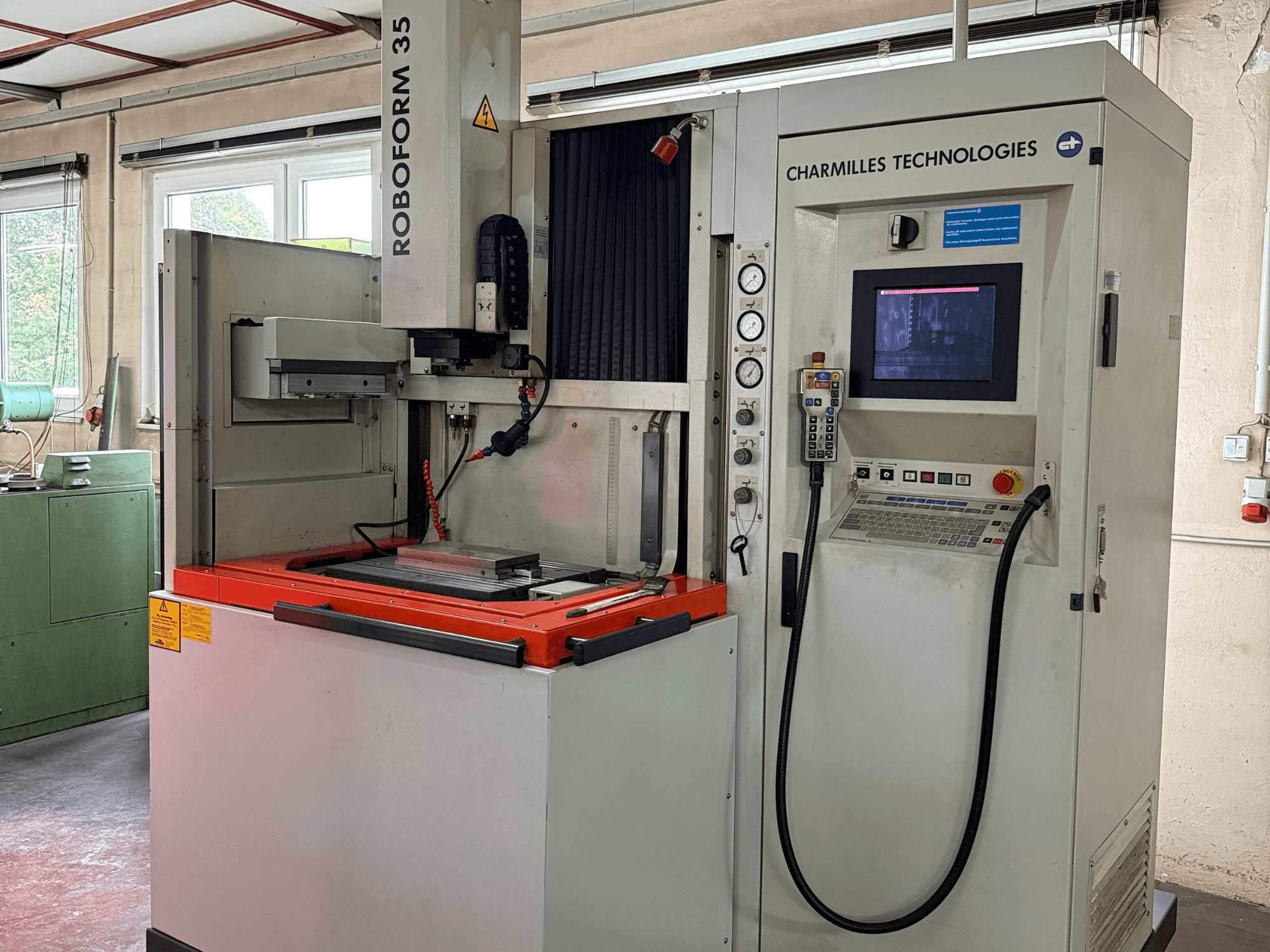 Станок Roboforn 35 компании Charmilles Technologies, вид спереди, панель управления, установленные инструменты и знаки безопасности.