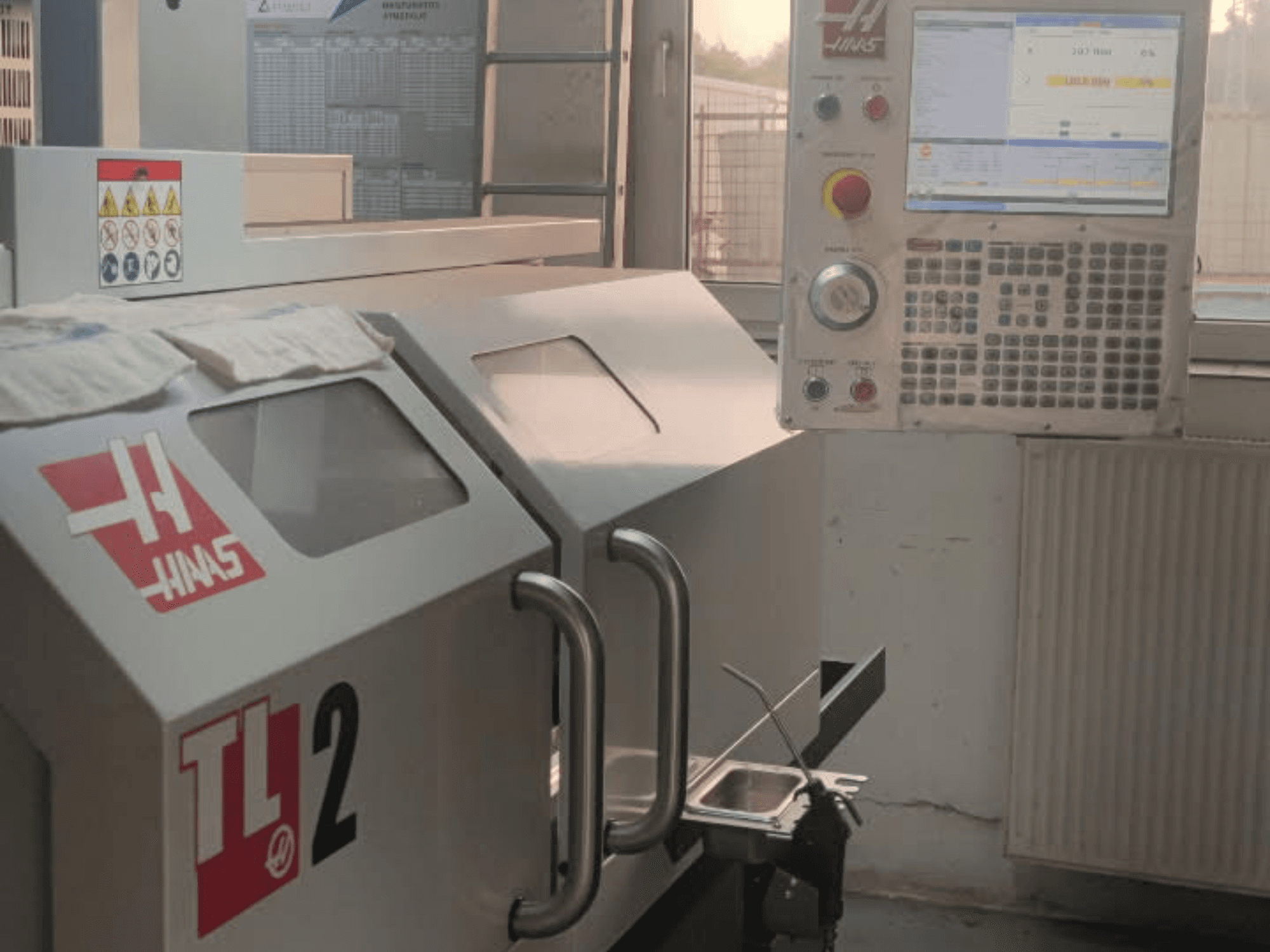 Горизонтальный токарный станок Haas TL-2 с видом спереди, с панелью управления, металлическим корпусом и знаками безопасности.