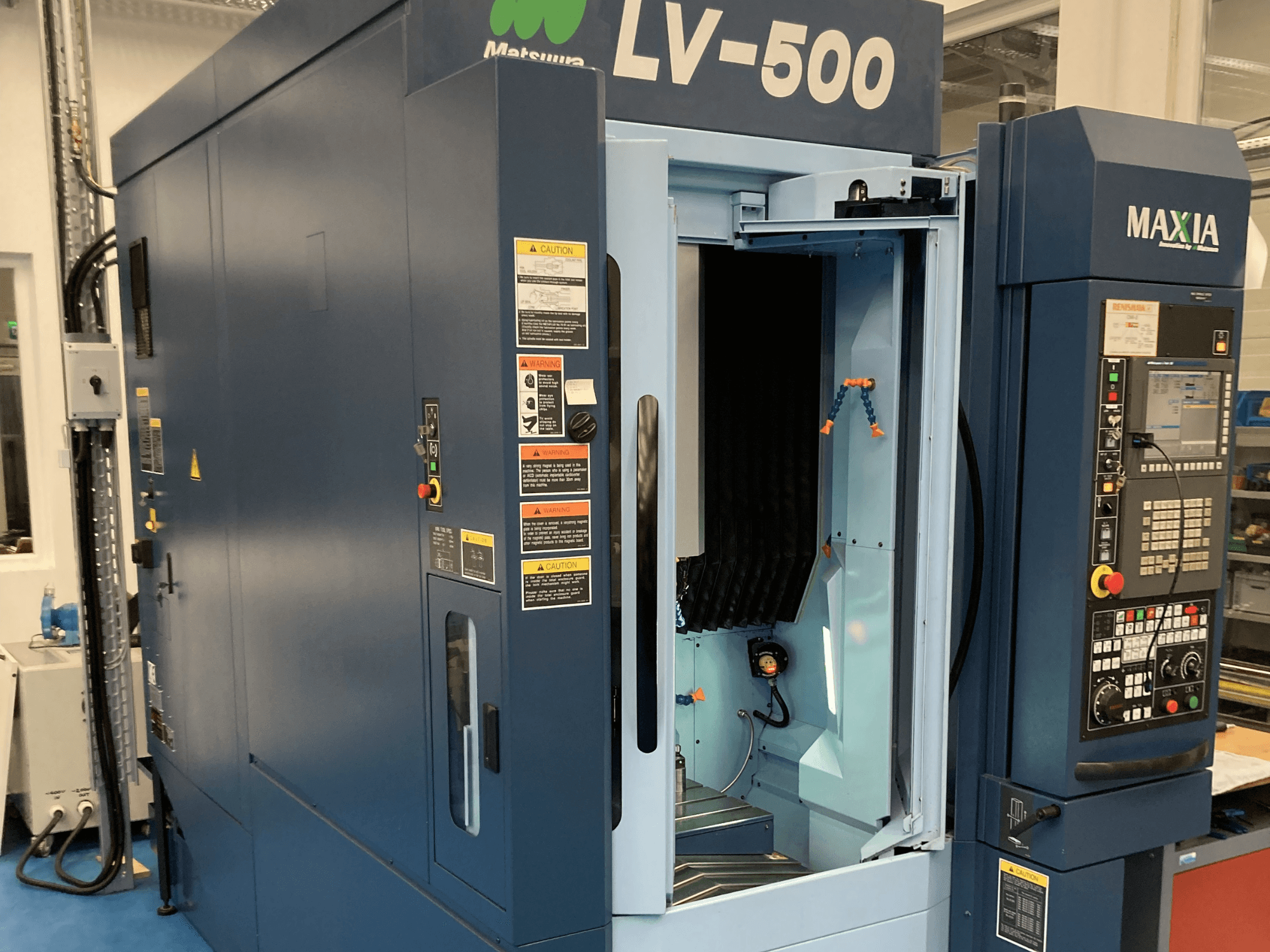 Вертикальный обрабатывающий центр Matsuura LV-500 с открытой дверью и панелью управления с кнопками, вид спереди.