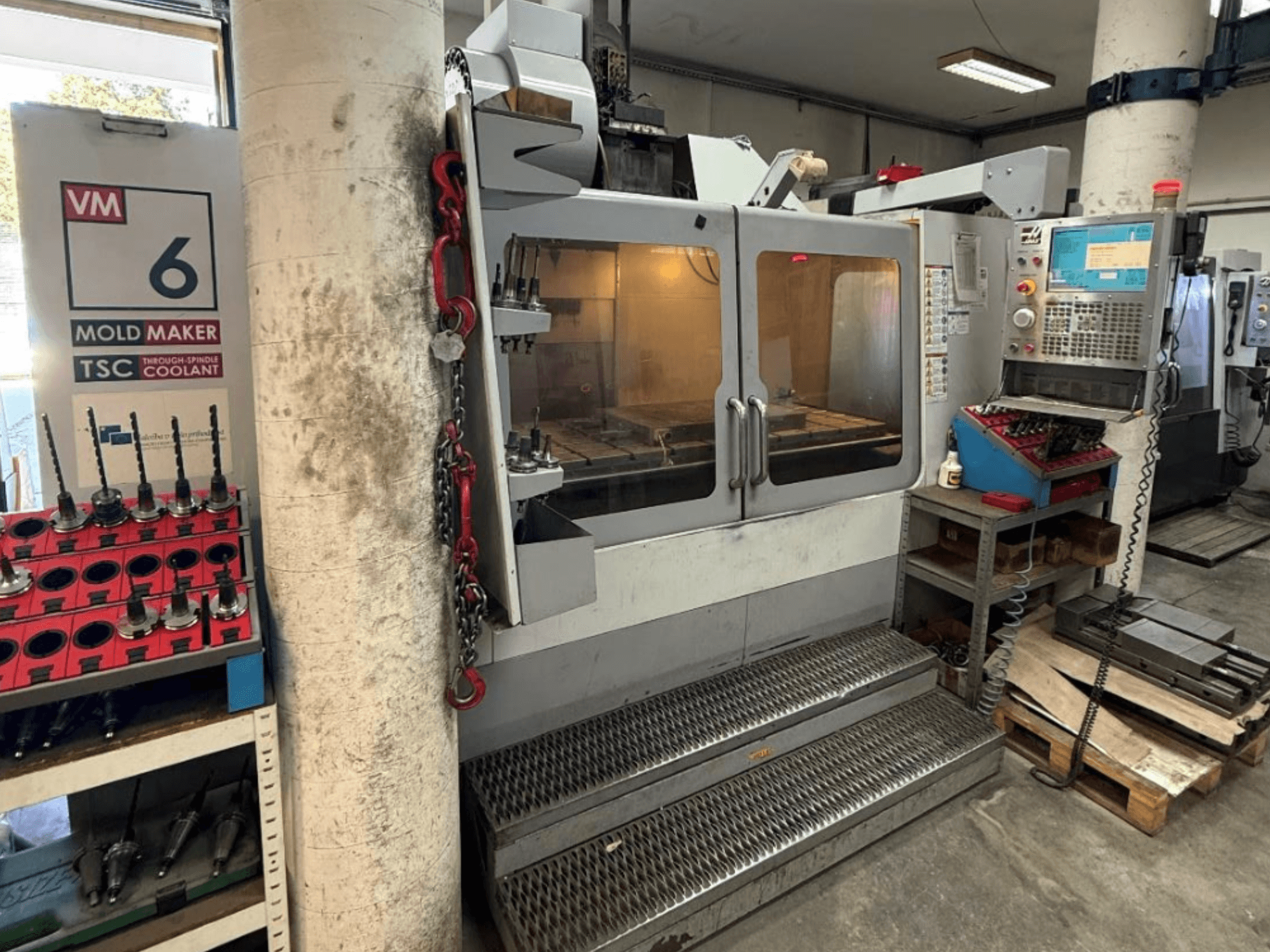 Вертикальный обрабатывающий центр HAAS VM-6 HE, вид спереди: видны органы управления, система охлаждения и хранилище инструментов.