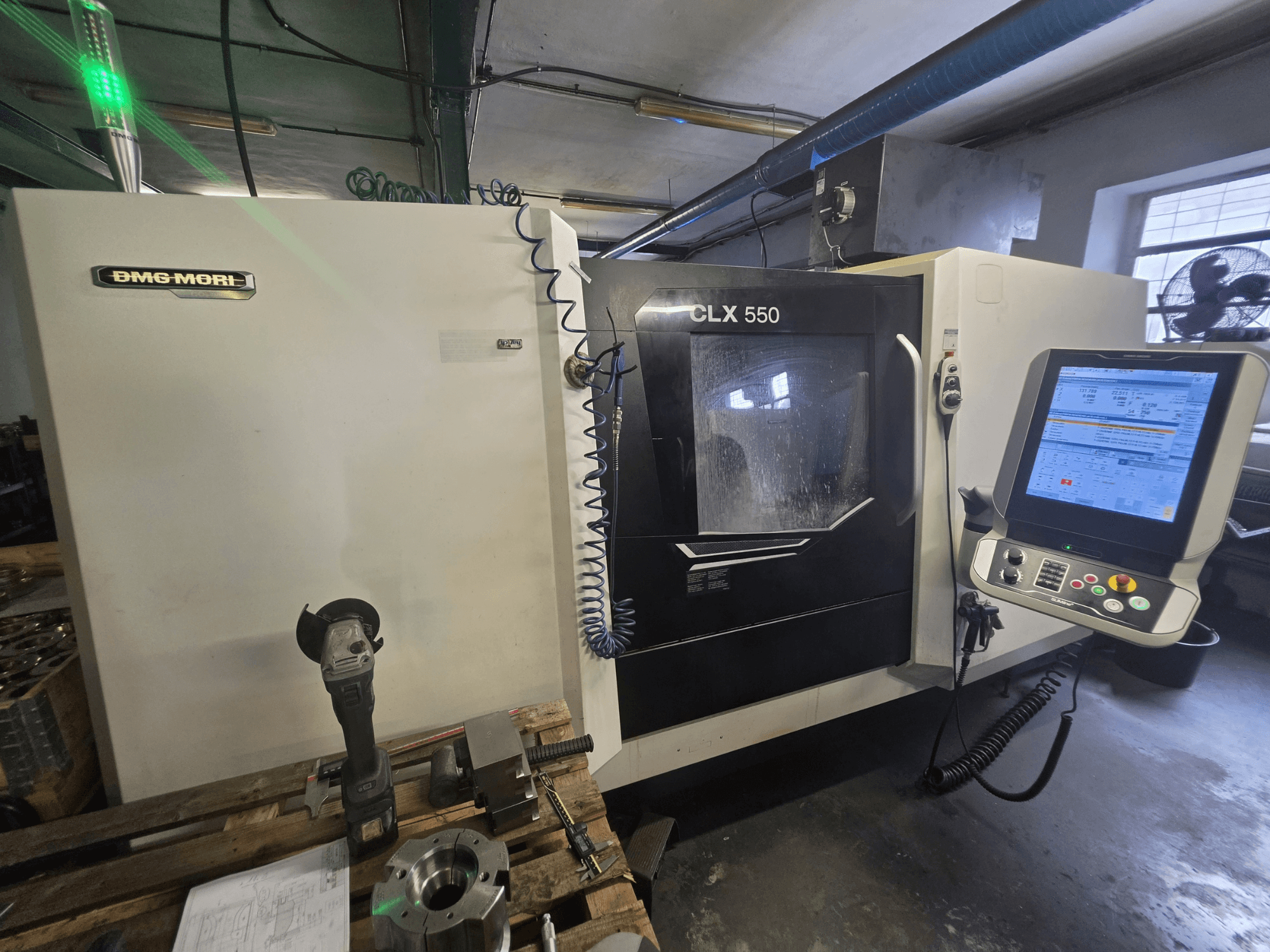 Горизонтальный токарный станок DMG MORI CLX 550 V3, вид спереди с панелью управления, режущими инструментами и корпусом станка.