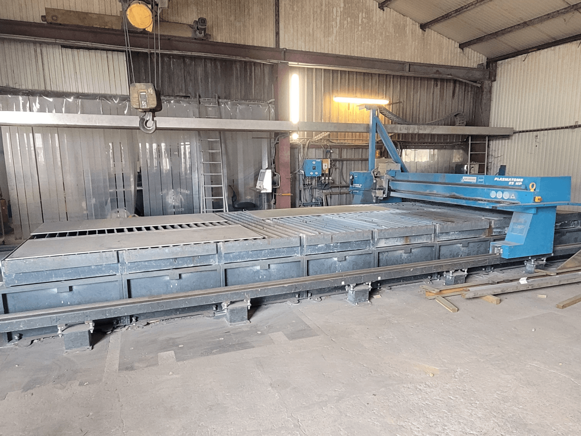 Машина плазменной резки SAF Plasmatone 25Hp, вид сбоку, демонстрирует режущую станину и рабочие компоненты в промышленной обстановке.