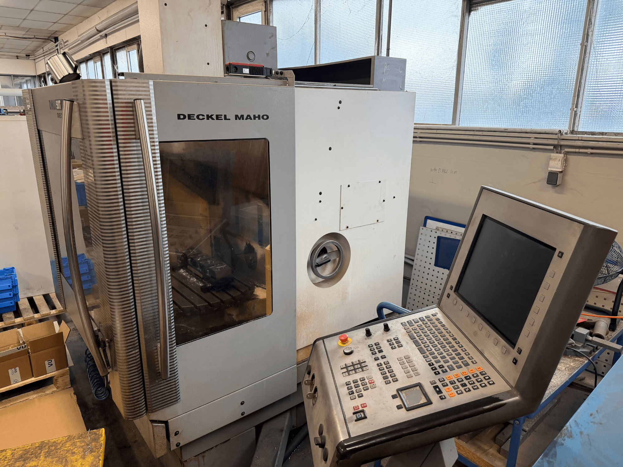 Универсальный обрабатывающий центр DECKEL MAHO DMU 50T в боковом виде с панелью управления и видимой зоной шпинделя.