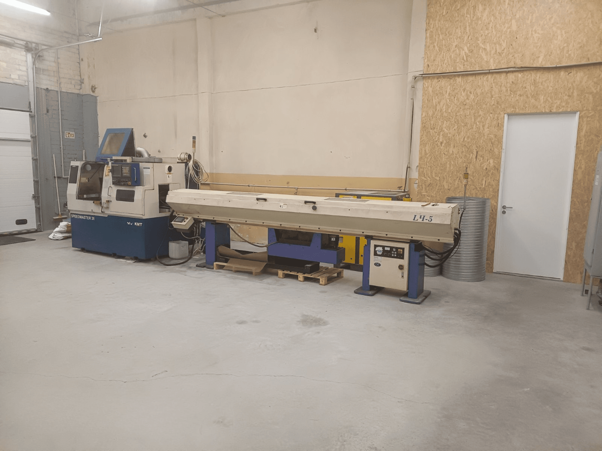 Промышленная мастерская с машиной KMT Speedmaster 34 и станком L4.5, вид спереди, видны органы управления и механизмы.