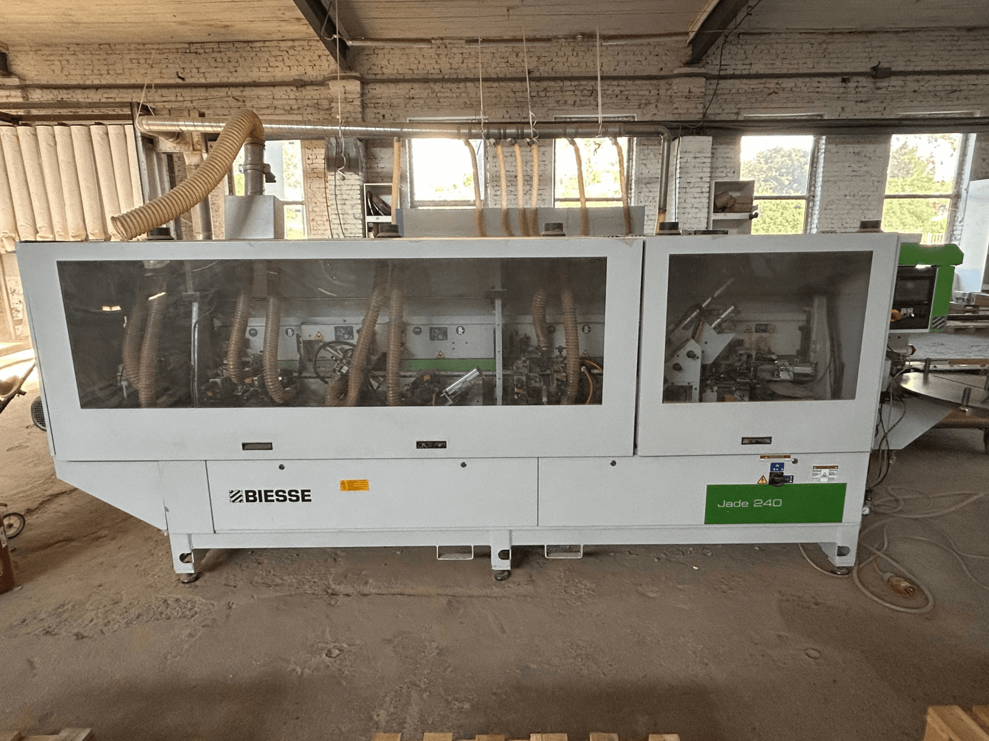 Кромкооблицовочный станок BIESSE Jade 240 в бело-зеленом цвете, вид спереди с панелью управления и детализированным изображением внутренних механизмов.
