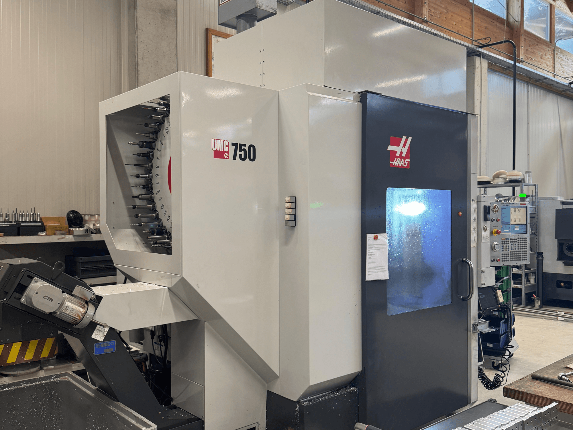 Обрабатывающий центр Haas UMC 750, вид спереди, демонстрирует держатель инструмента и панель управления в мастерской.