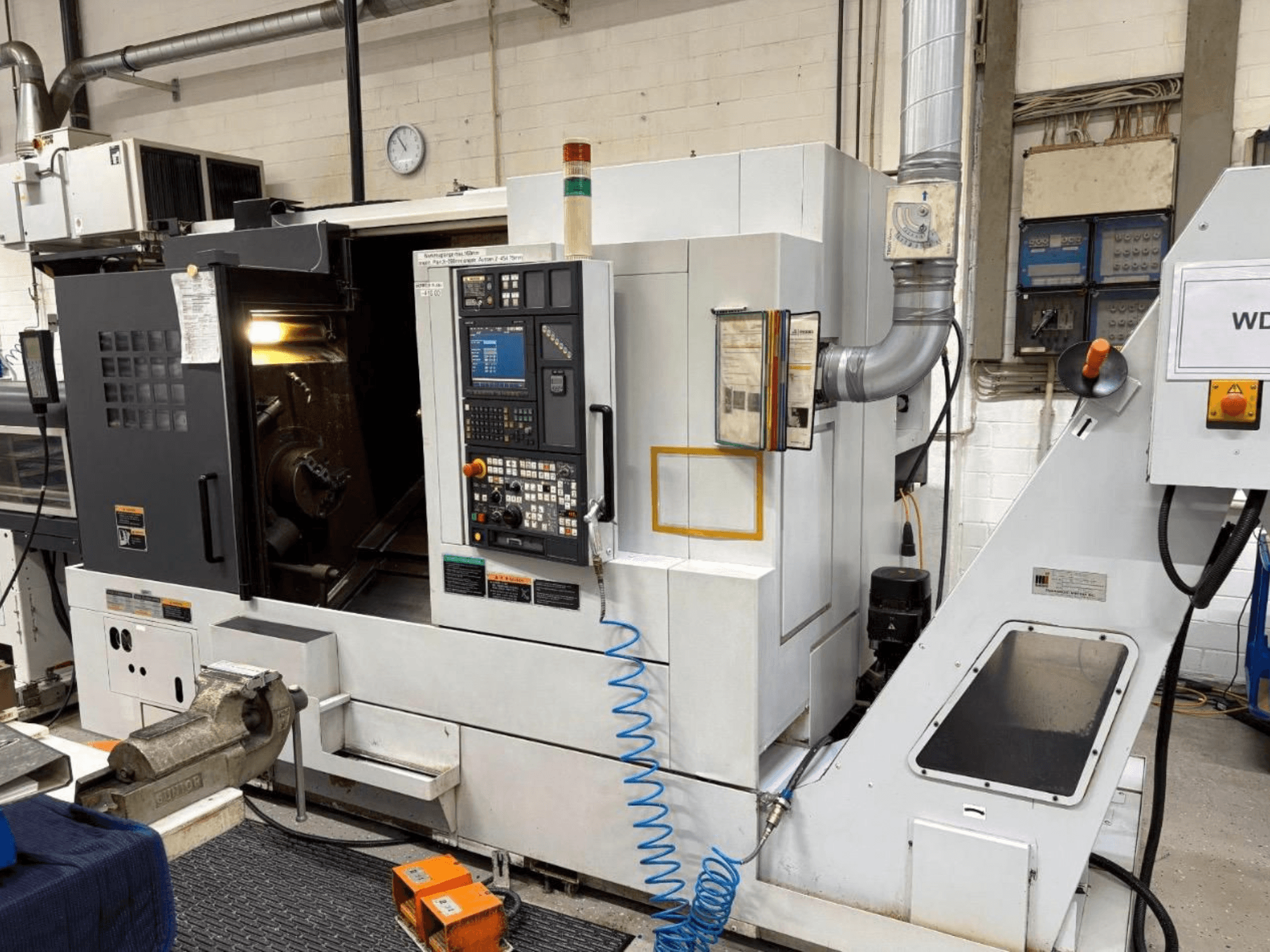 Токарно-фрезерный центр MORI SEIKI NL 2500 SY, вид спереди, показывает панель управления и зону обработки. Видимая система охлаждения и принадлежности.