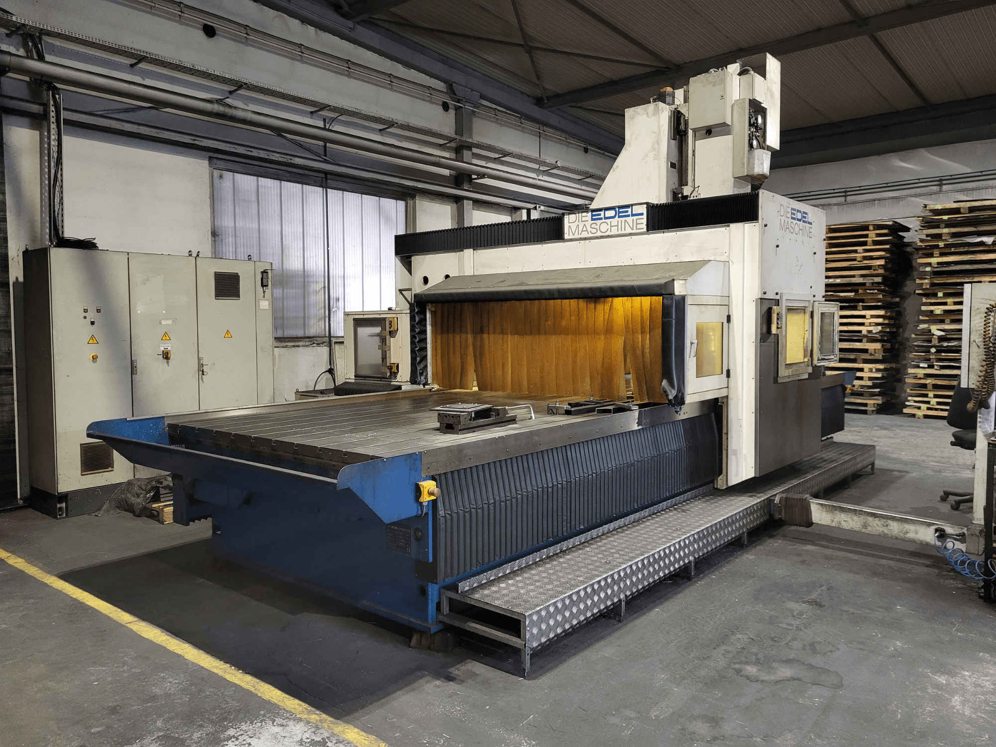 Портальный фрезерный станок EDEL Koordimatic XL 4020, вид спереди, демонстрирующий большой рабочий стол и блок управления в промышленной обстановке.