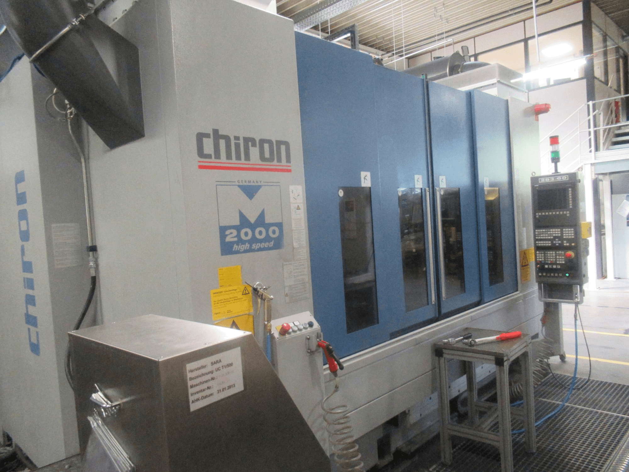Вертикальный обрабатывающий центр CHIRON Mill 2000, вид спереди с панелью управления, в синем исполнении, на котором видны элементы, обеспечивающие высокую скорость работы.