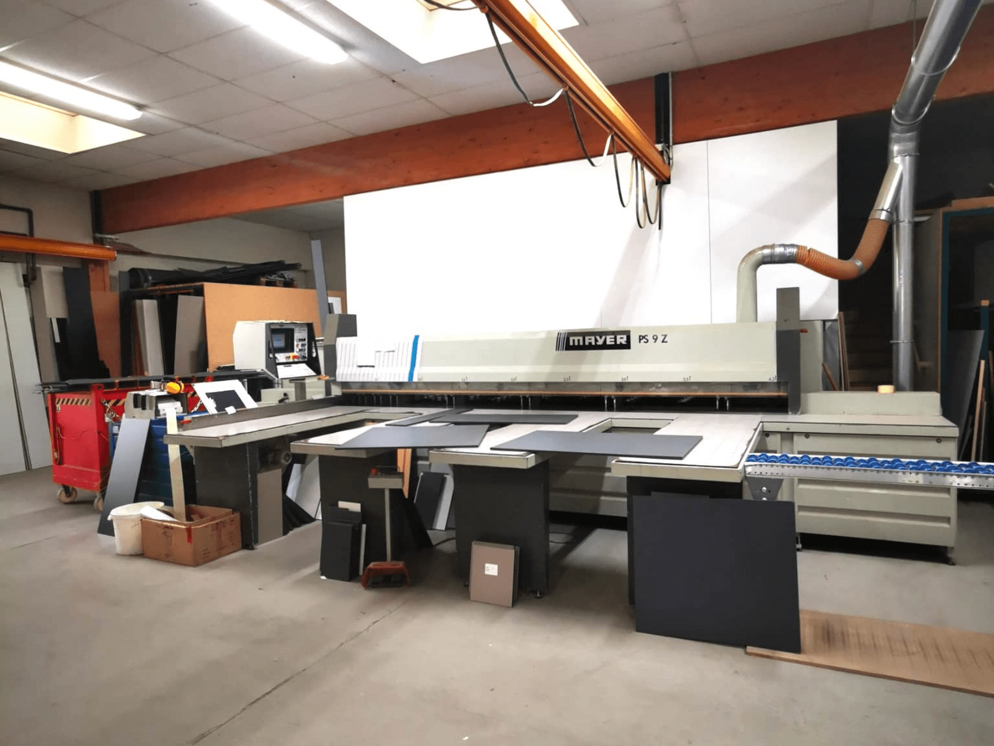 Станок для резки MAYER PS9 Z в мастерской, вид спереди, видны различные материалы и конвейер.