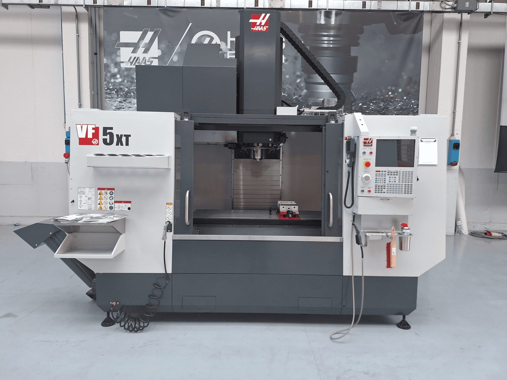 Вертикальный обрабатывающий центр HAAS VF-5/50XT, вид спереди, на котором видны панель управления, зона шпинделя и хранилище инструментов.