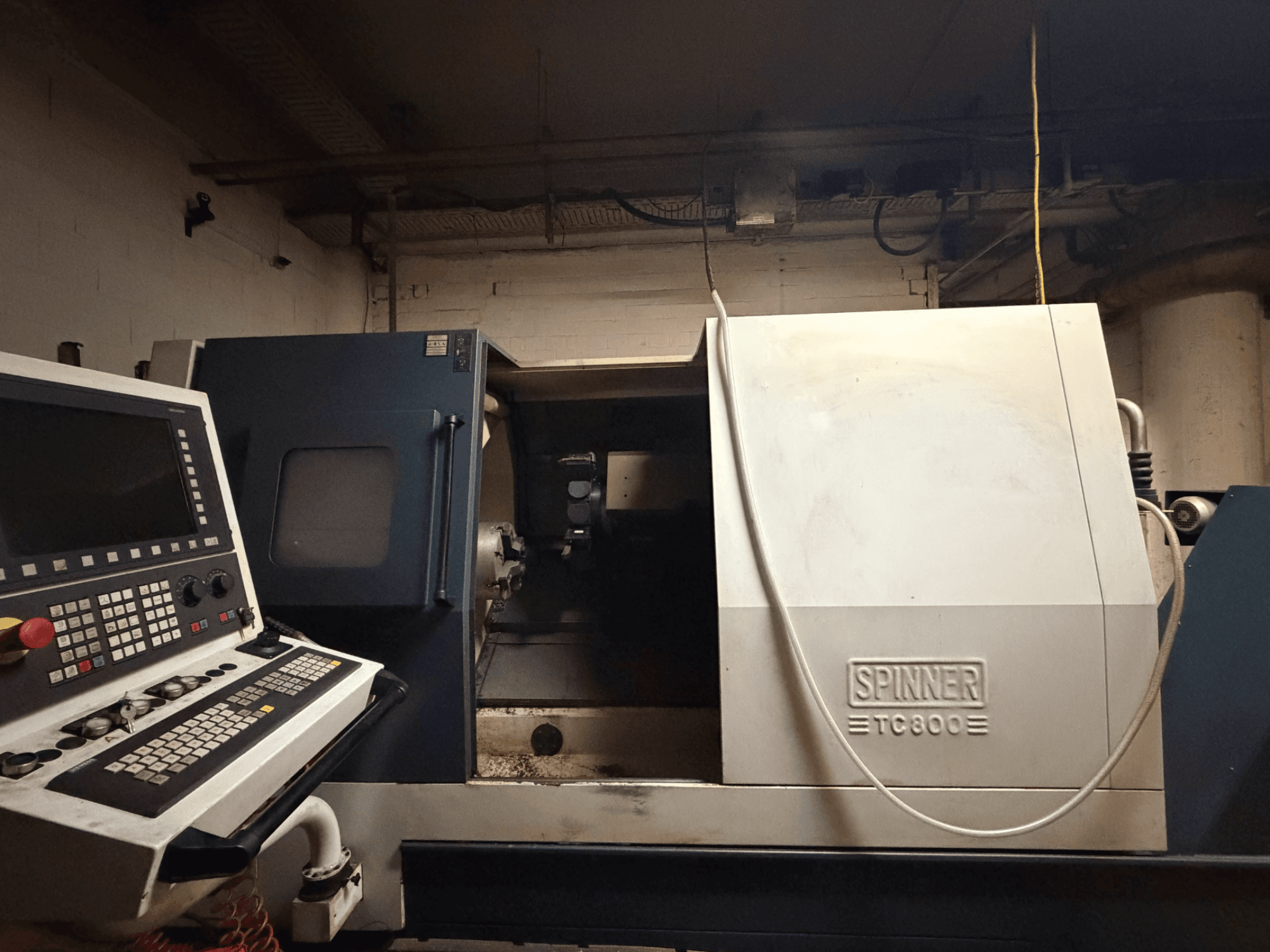 Горизонтальный токарный станок SPINNER TC800, вид спереди, видна панель управления, внутренняя часть станка слегка обнажена.
