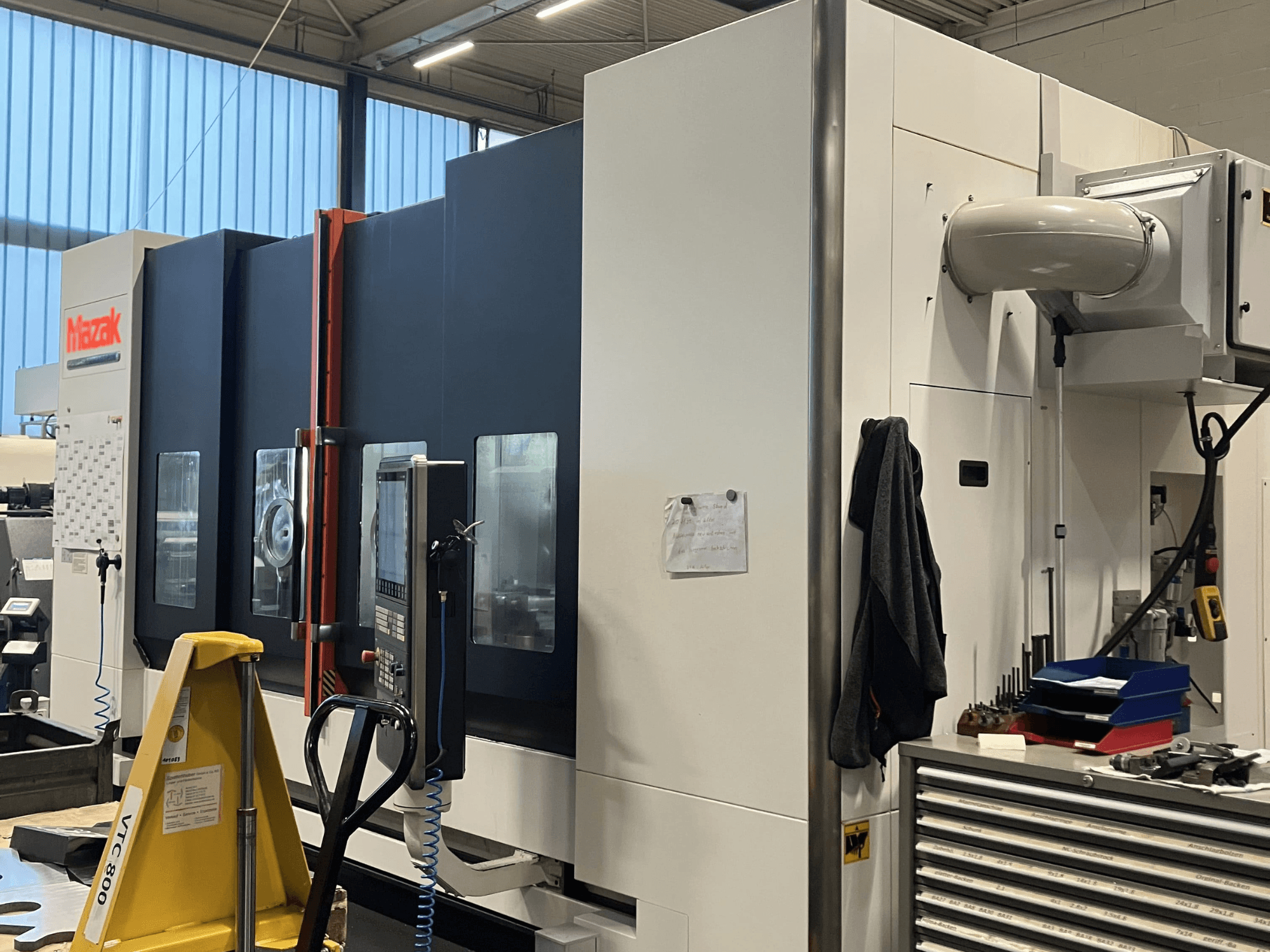 Станок с ЧПУ Mazak с видом сбоку, демонстрирующий панель управления и функции безопасности в условиях мастерской.
